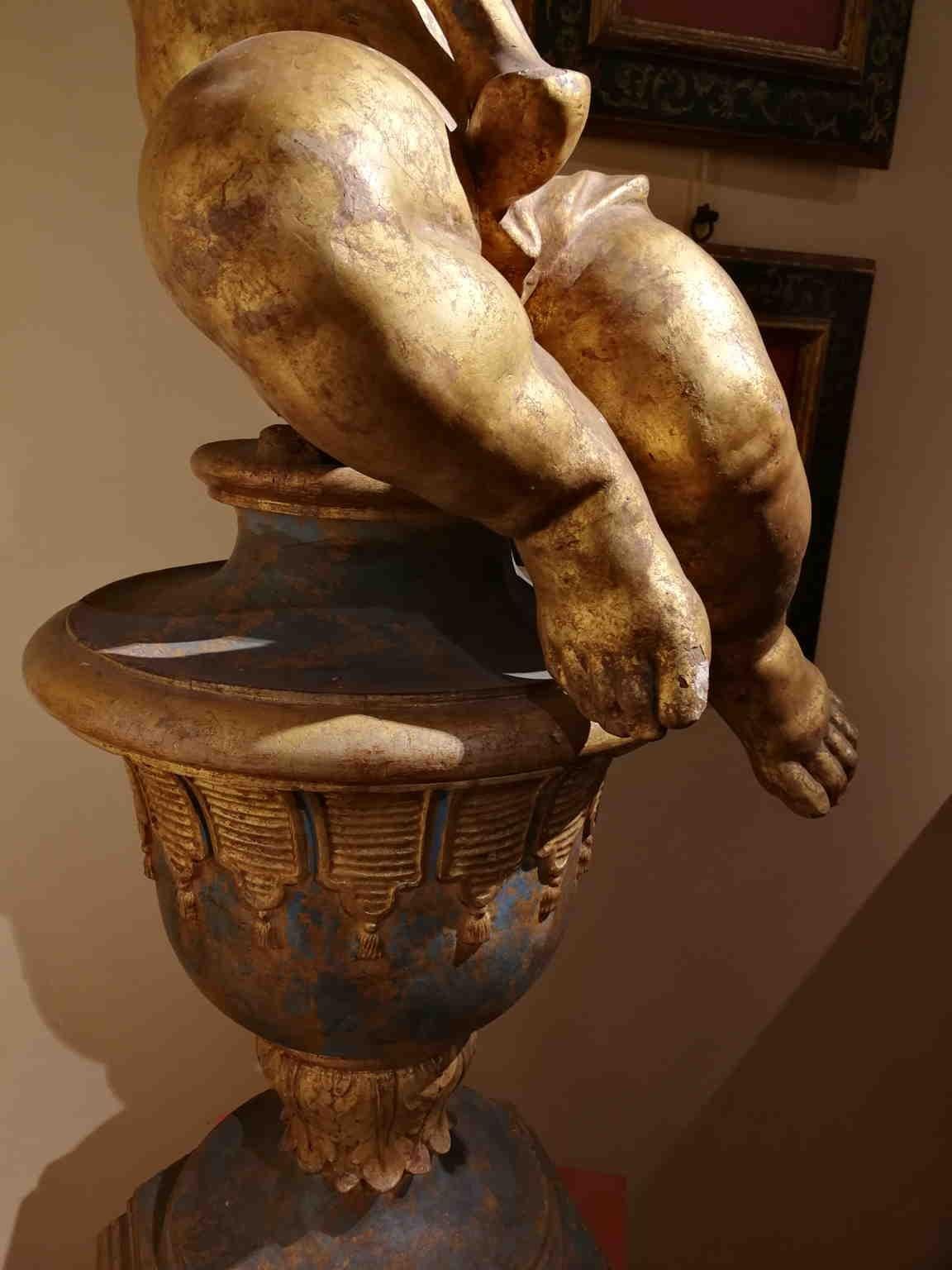 Eine Flamme Kerzenhalter Putto aus vergoldetem Holz.
Diese Art von Objekten war vor allem in der Barockzeit in Kirchen und Adelsvillen zu finden. 

Die Basis ist nicht gleichaltrig.
