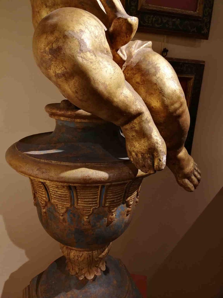 One flame candle holder putto made of gilded wood.
Those kind of objects were present in churches or noble villas, specially during the Baroque times. 

The base is not coeval.
