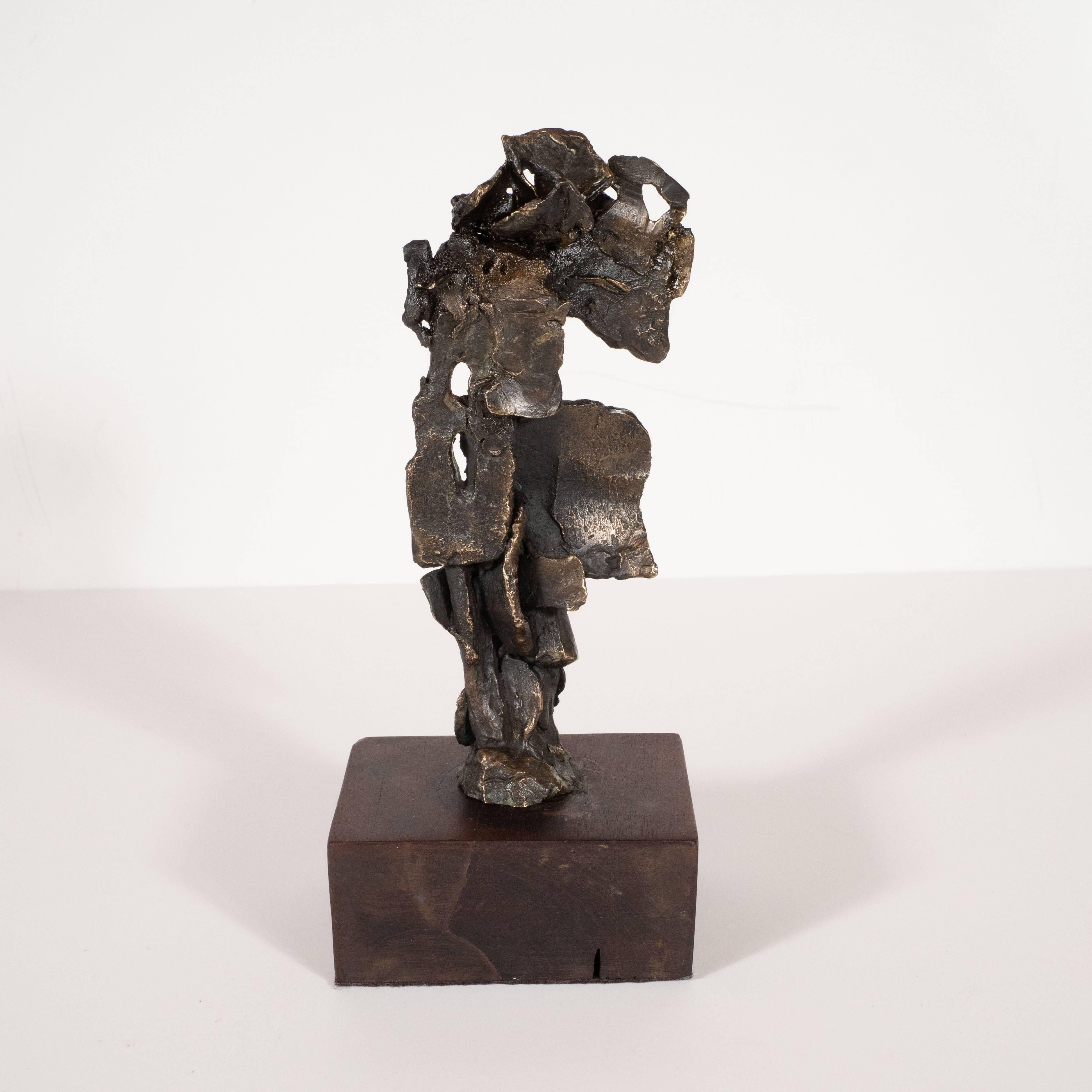 This sophisticated abstract bronze sculpture was realized in the United States, circa 1960. It features abundance of adjoined organic bronze forms resting on a rectangular original walnut base. With its totemic silhouette, it suggests an abstracted