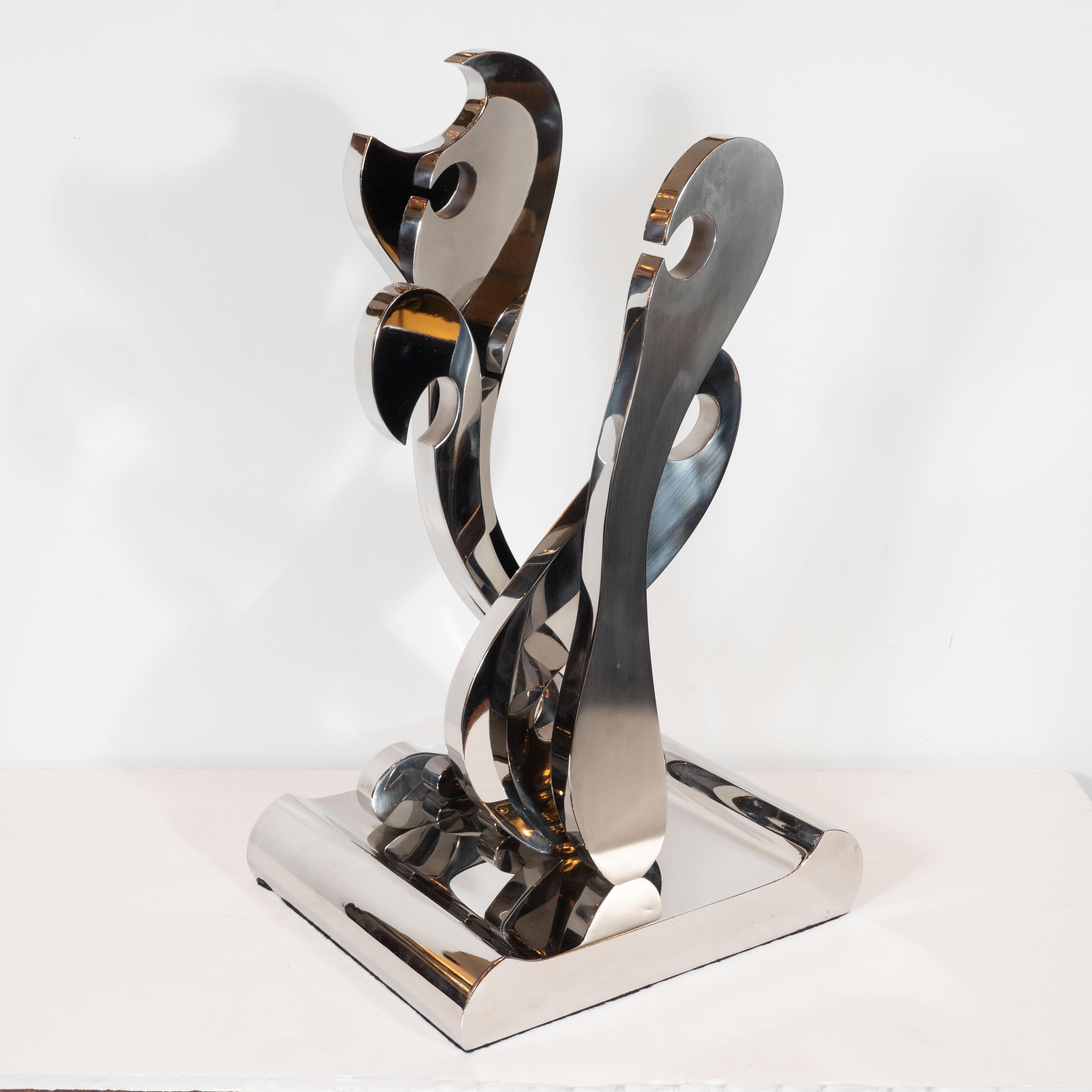 This compelling Mid Century Modern sculpture was realized in the United States circa 1970.  Sitting on a volumetric rectangular chrome base with raised and rounded sides, the piece offers four abstract forms that appear in the midst of ecstatic