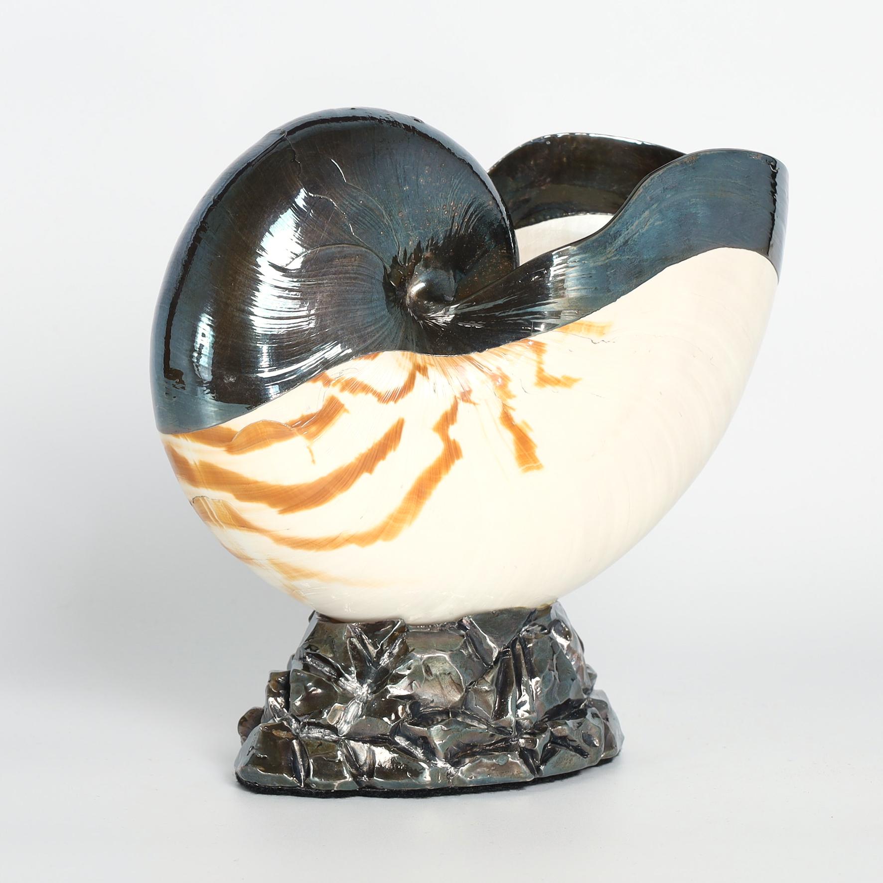 Mid century Italian nautilus shell enhanced with silver plate overlay and presented on a silvered faux rock base. Signed Ruzzetti & Gow on the bottom. 