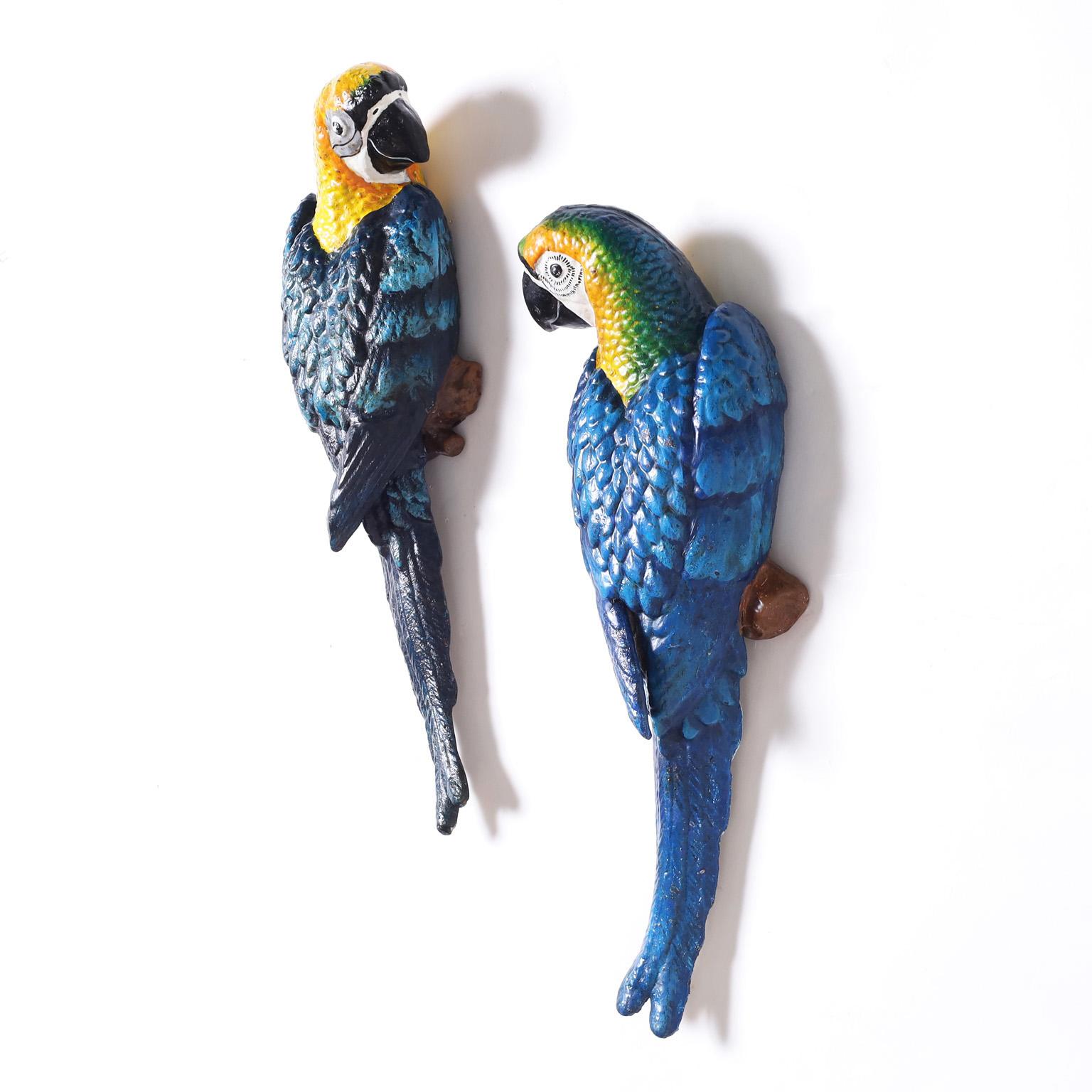 Striking pair of vintage life-size parrot wall hanging sculptures crafted in cast iron and painted in tropical colors now slightly oxidized. 