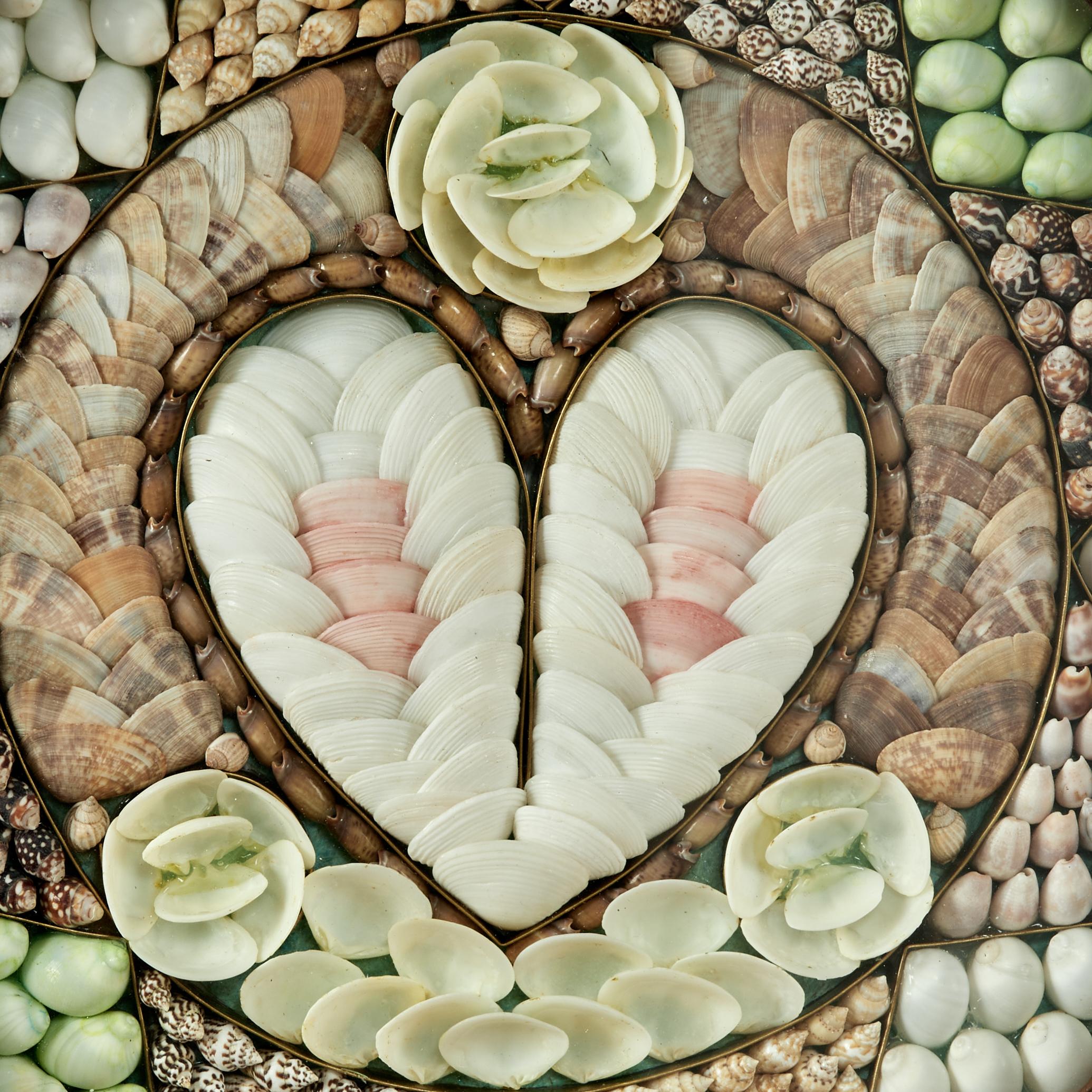 Un'affascinante valentina vintage per marinai ambiziosamente realizzata a mano in conchiglie esotiche organiche con un motivo centrale a cuore circondato da scomparti a forma di stella. Presentato sotto vetro in una scatola ottagonale in mogano.