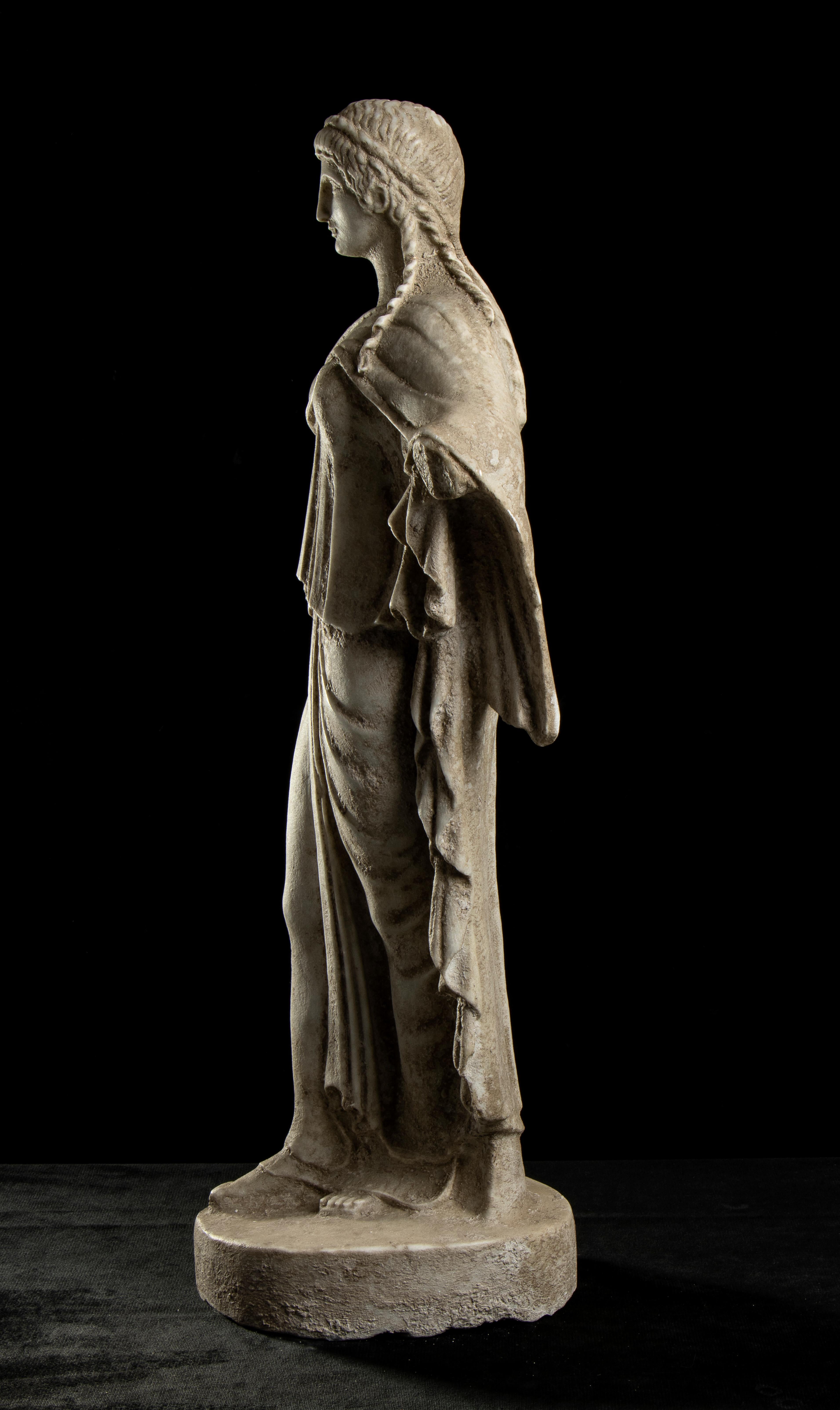 an interesting sculpture carved in white marble with an deep aged finishing of the greek goddess Artemis the in the grand tour style. The figure, dressed in a long-sleeved chiton, with dense folds in close parallel lines, which envelops the whole