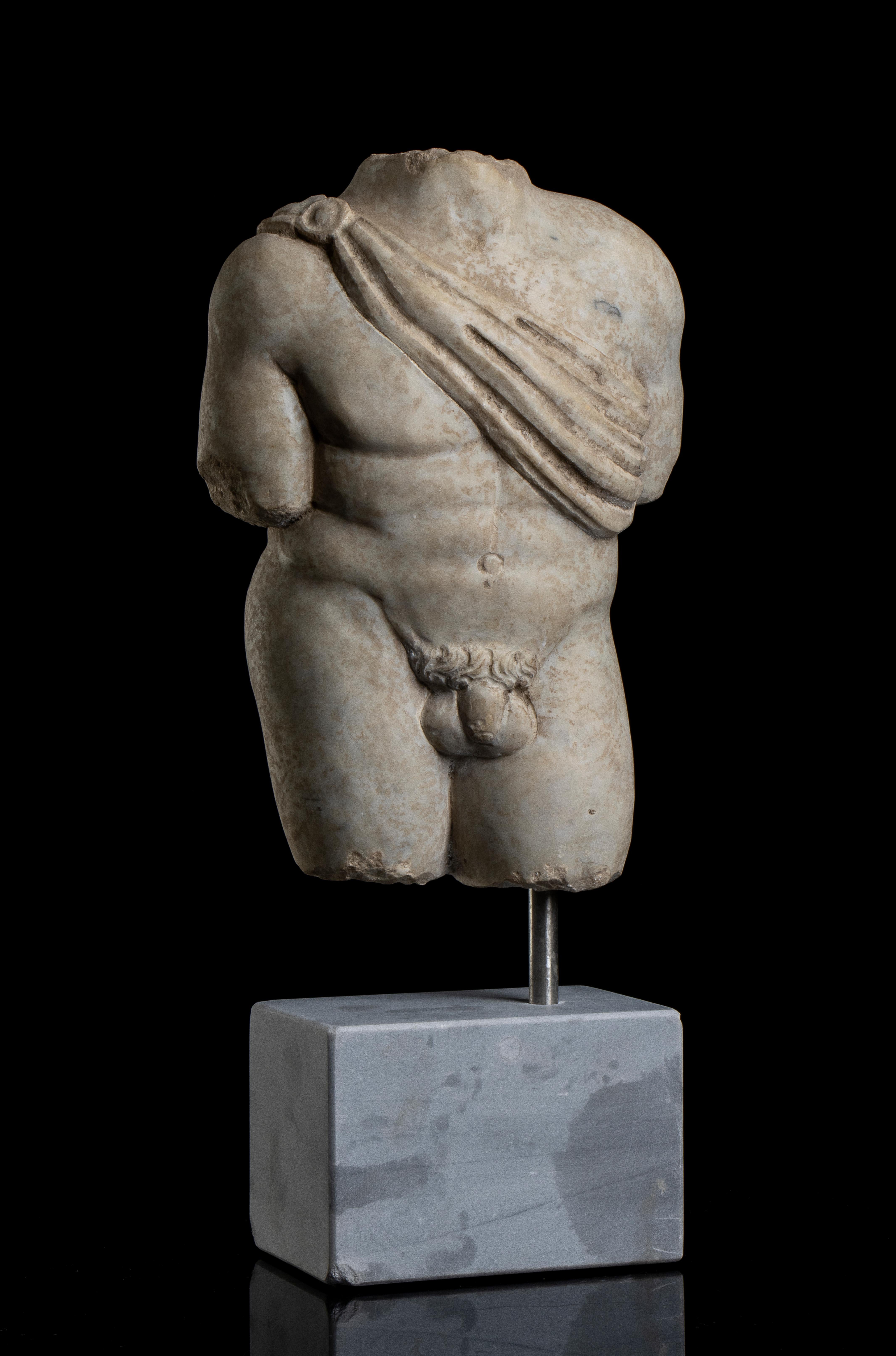 Sculpture torse nu du dieu Apollo en marbre blanc de style grand tour, grec classique sculptée au 20e siècle, probablement  Italie centrale.  
Apollo représenté nu avec une description anatomique pertinente et avec  un support tissé pour le