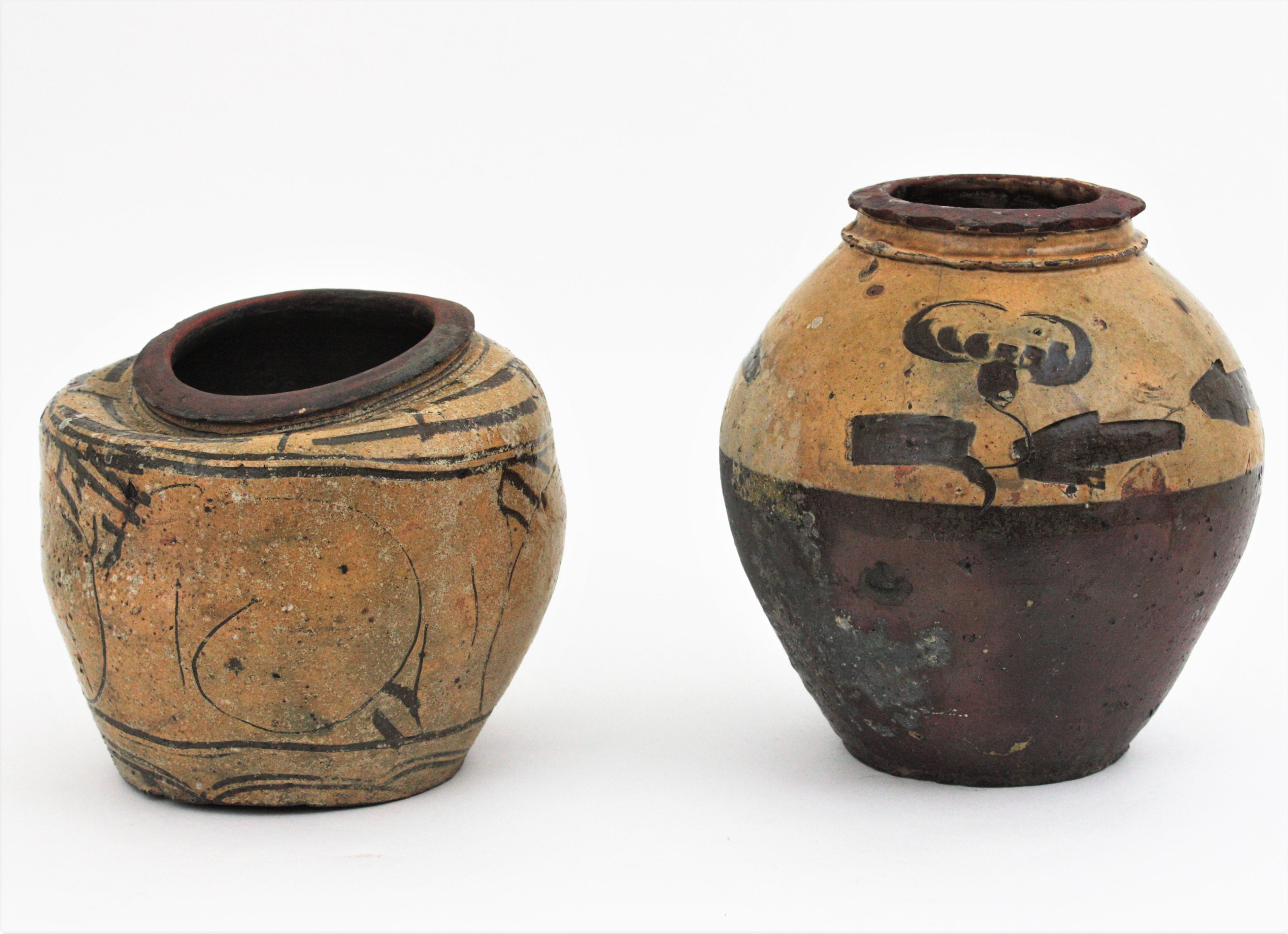Pair of urn shapped terracotta pots or vessels wiht glazed decorations, China, 1930s.
Provincial rustic handmade terracotta wine jars or preserving pots.
The taller one is covered by glazed ceramic in cream color from the medium part to the top. It