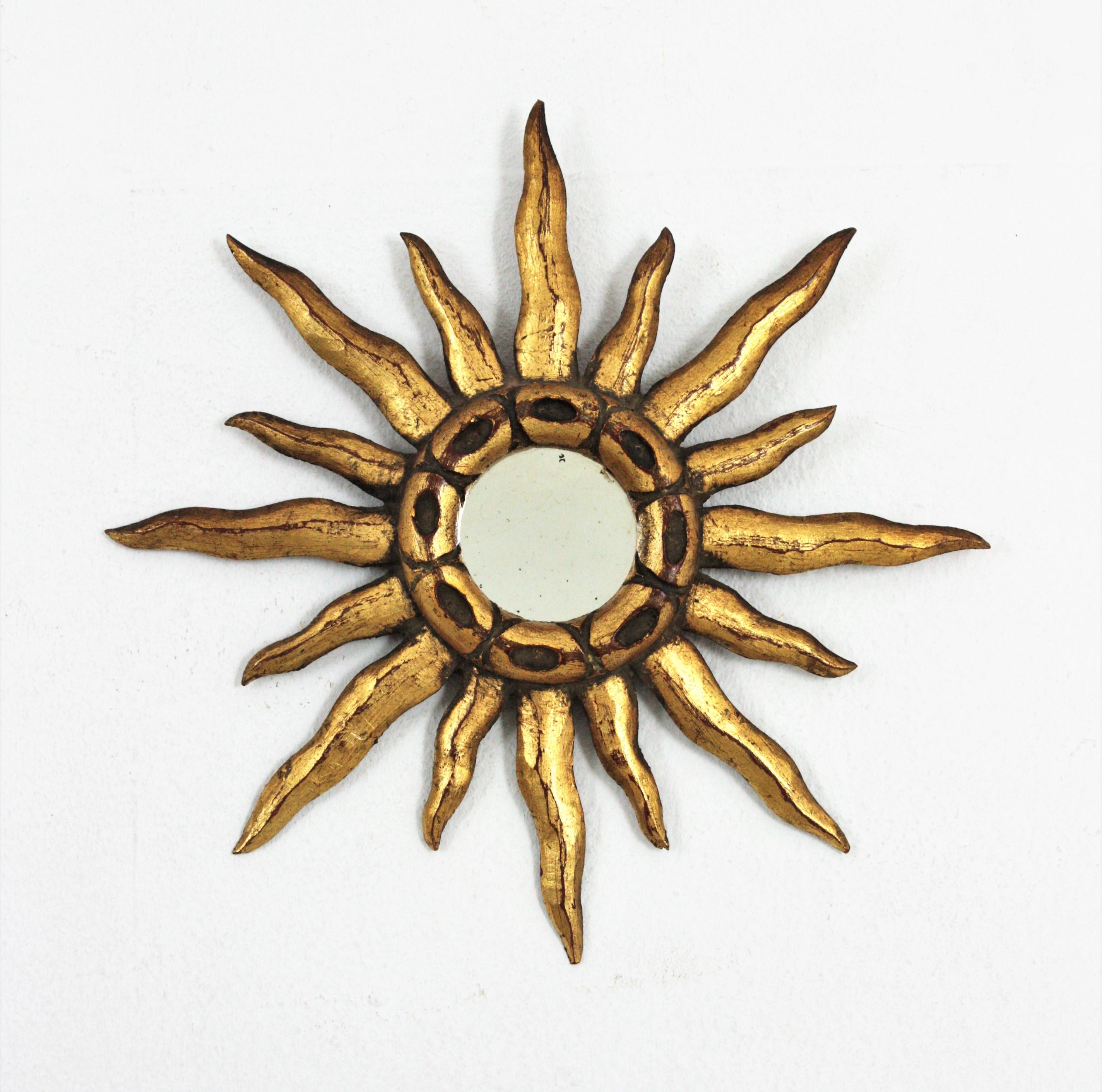 Unmatching pair of small scale sunburst mirrors in carved giltwood, Spain, 1940-1950s.
Eye-catching pair of mini sized sunburst mirrors in baroque style. Each one has a different design with carving details. One has a carved pattern at the central