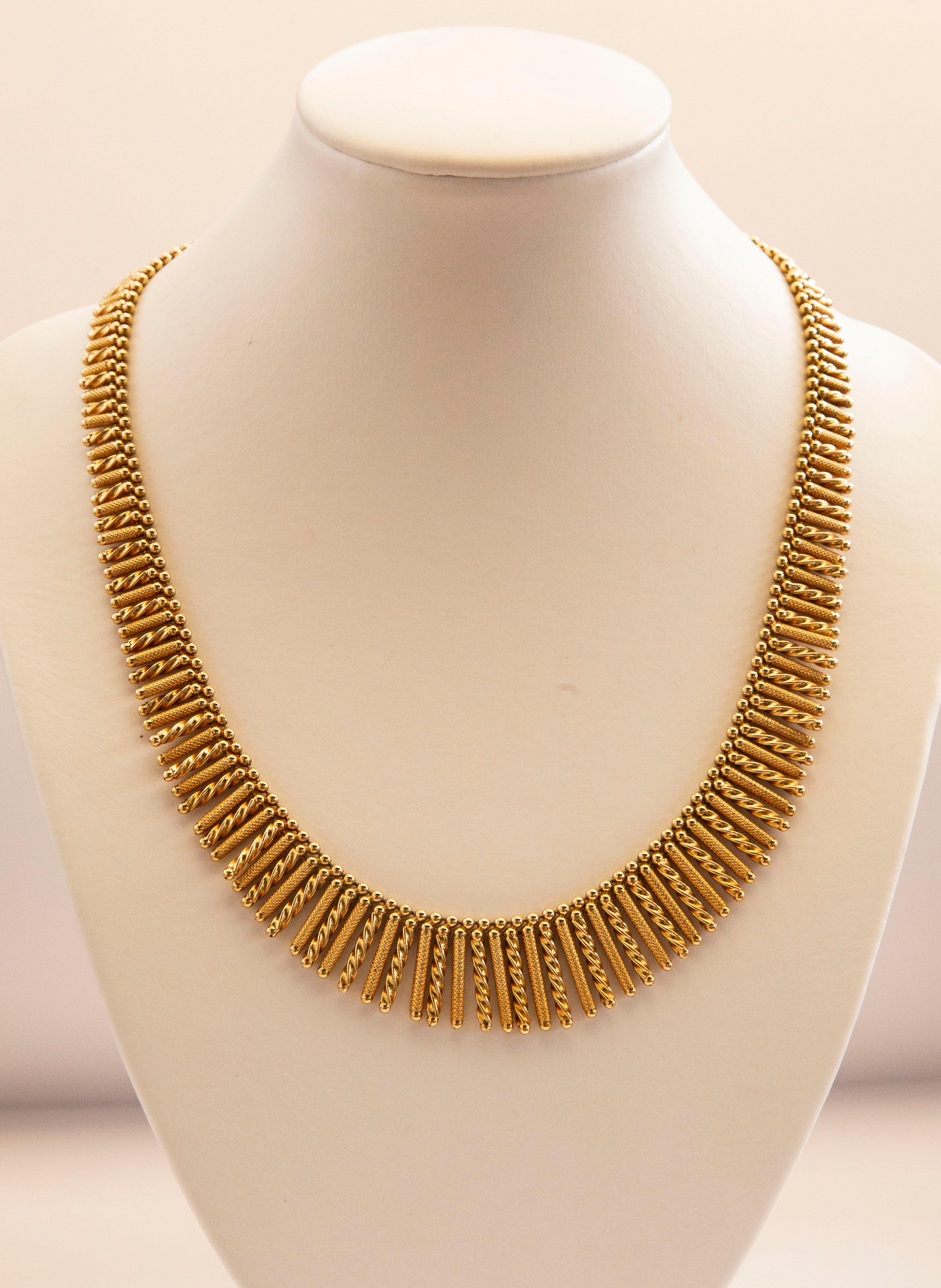 A vintage Italian 18 karat solid yellow gold graduated fringe necklace manufactured by Uno-A-Erre in the 1960s. The necklace consists of textured and twisted open ended rods suspended from a single strand of beads. It has an insert clasp and safety