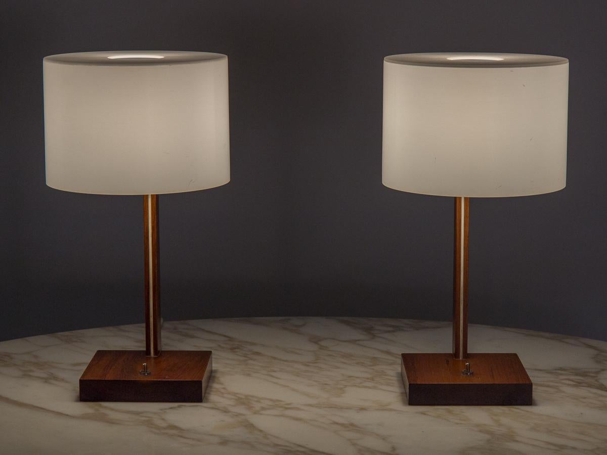 Pair of Scandinavian Modern table lamps designed by Uno and Osten Kristiansson for LUXUS. Minimal silhouette nicely shows off the pretty grain of the rosewood base. Emitting a soft glow without glare from the acrylic drum shade, this pair would make