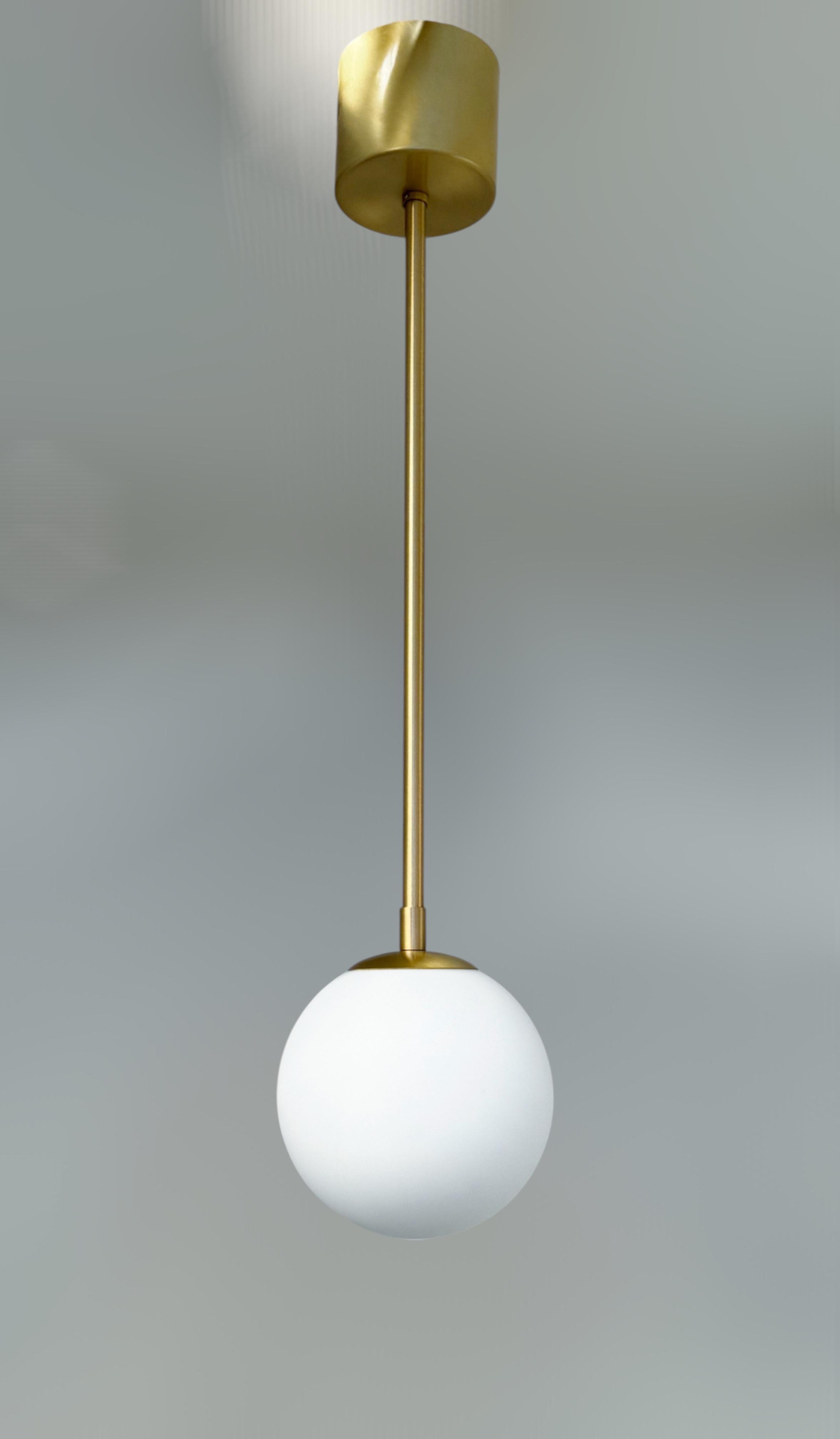 Italienische Pendelleuchte mit einer Kugel aus mattweißem Murano-Glas auf einem satinierten Messingrahmen / Made in Italy 
Entworfen von Fabio Ltd, inspiriert von den Stilen Angelo Lelli und Arredoluce 
1 Leuchte / Typ E12 oder E14 / je max. 40W