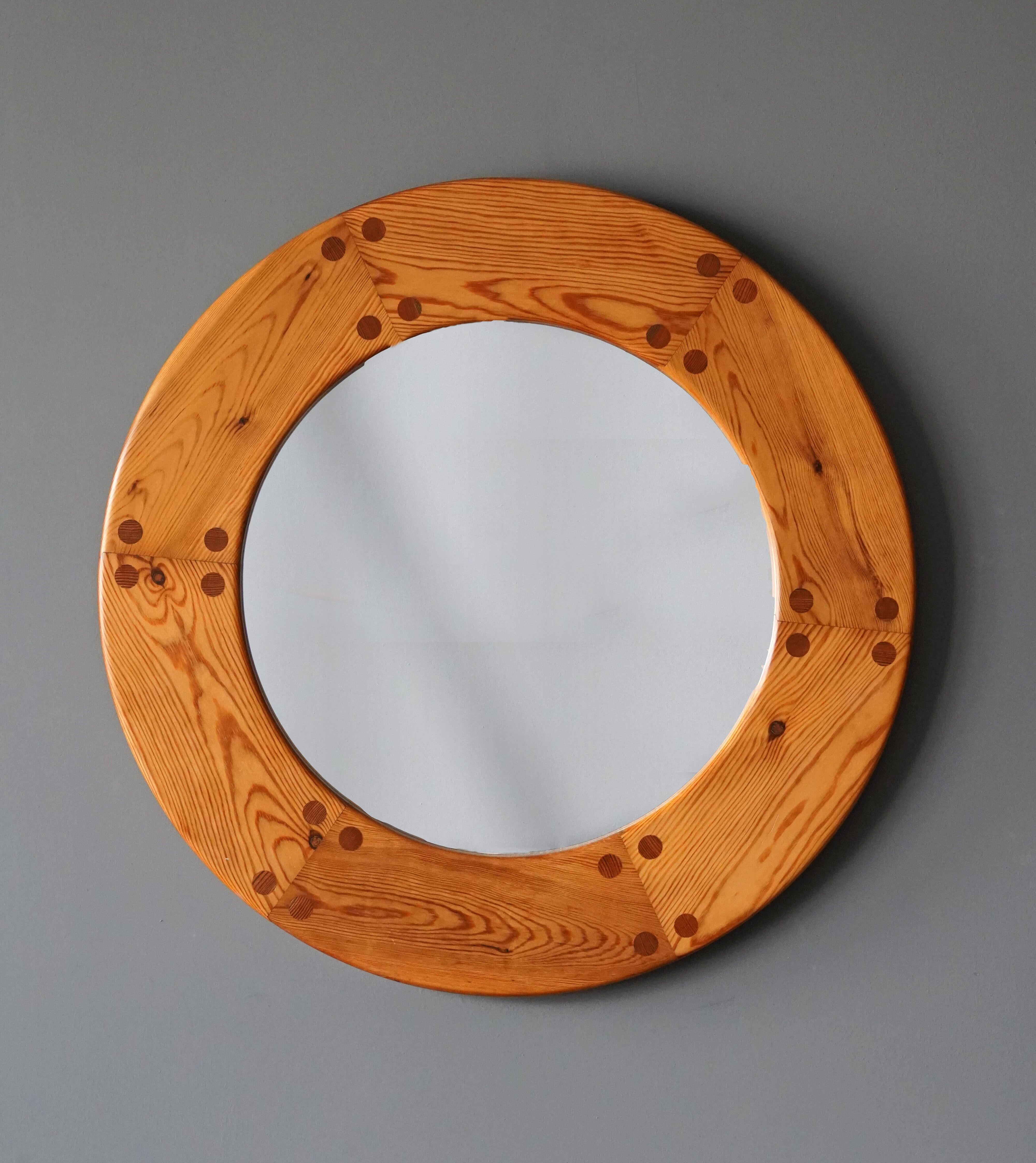 A sculptural round wall mirror. Designed by Uno Kristiansson, for Luxus, Sweden, 1960s. Features revealed teak-colored joinery. 

Other designers of the period include Axel Einar Hjorth, Roland Wilhelmsson, Charlotte Perriand, Pierre Chapo, and