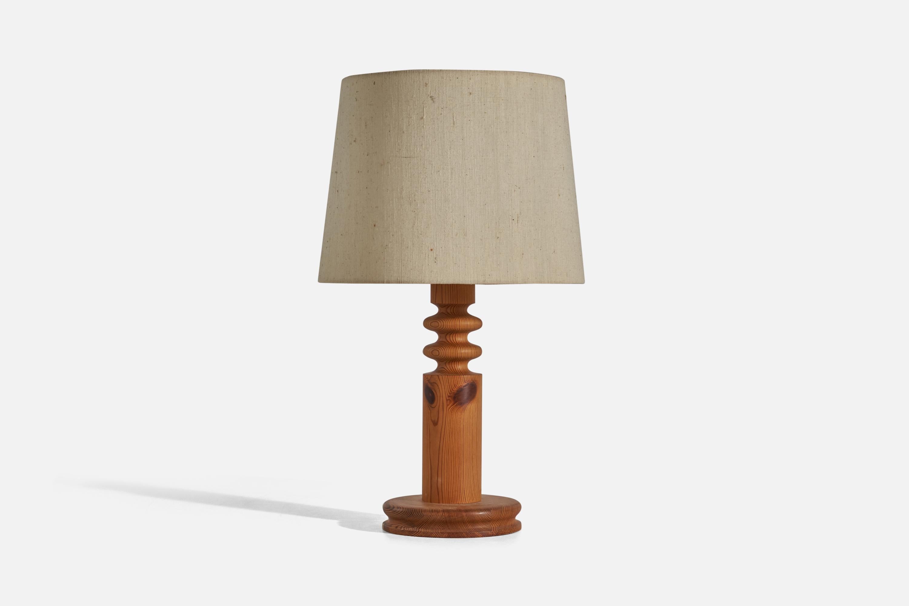 A solid pine and beige fabric table lamp designed by Uno Kristiansson and produced by Luxus, Sweden, 1960s.

Sold with Lampshade. Dimensions stated are of Table Lamp with Lampshade. 

Socket takes standard E-26 medium base bulb.

There is no maximum