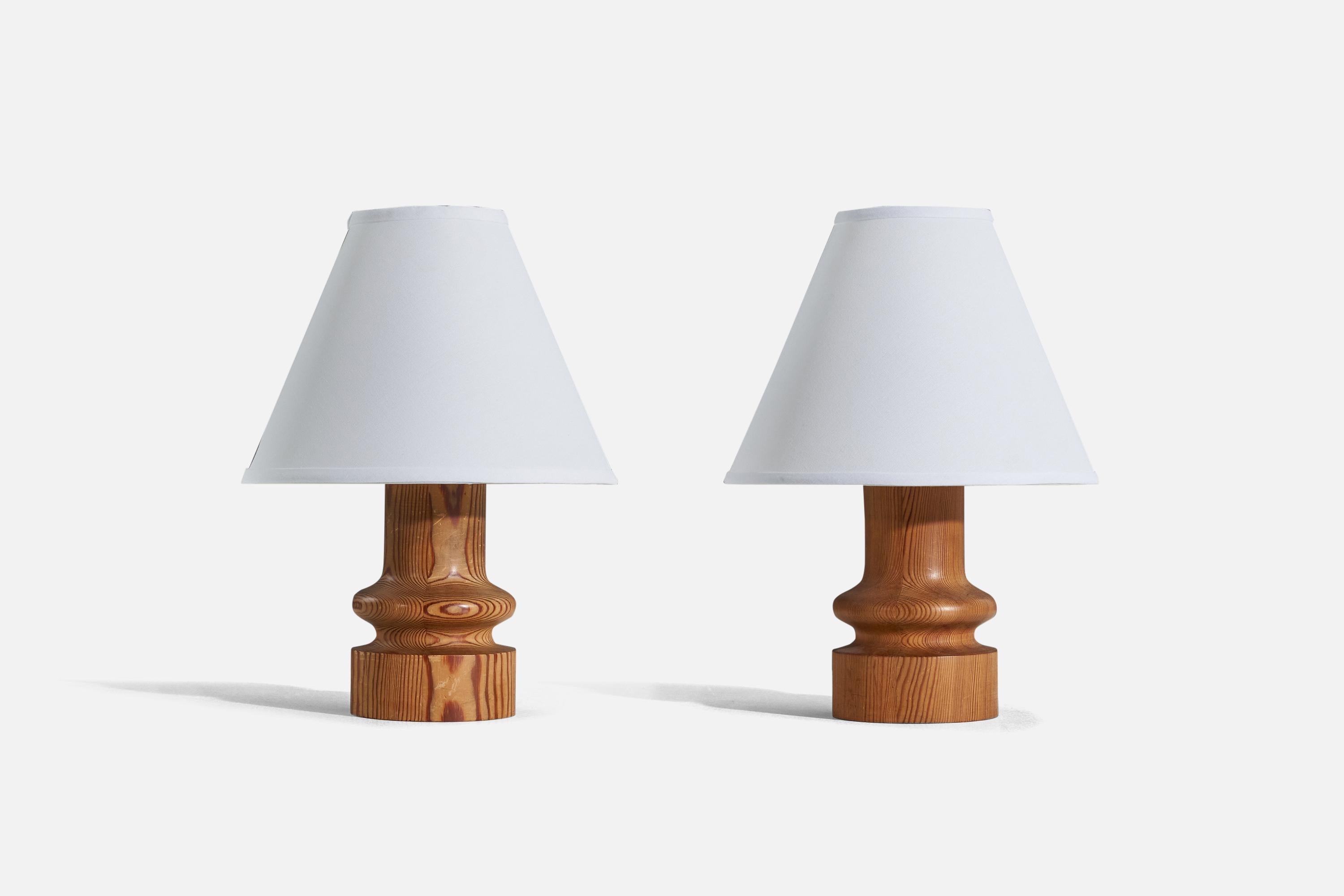 A pair of turned solid pine and fabric table lamps, designed by Uno Kristiansson and produced by Luxus, Sweden, 1970s. 

