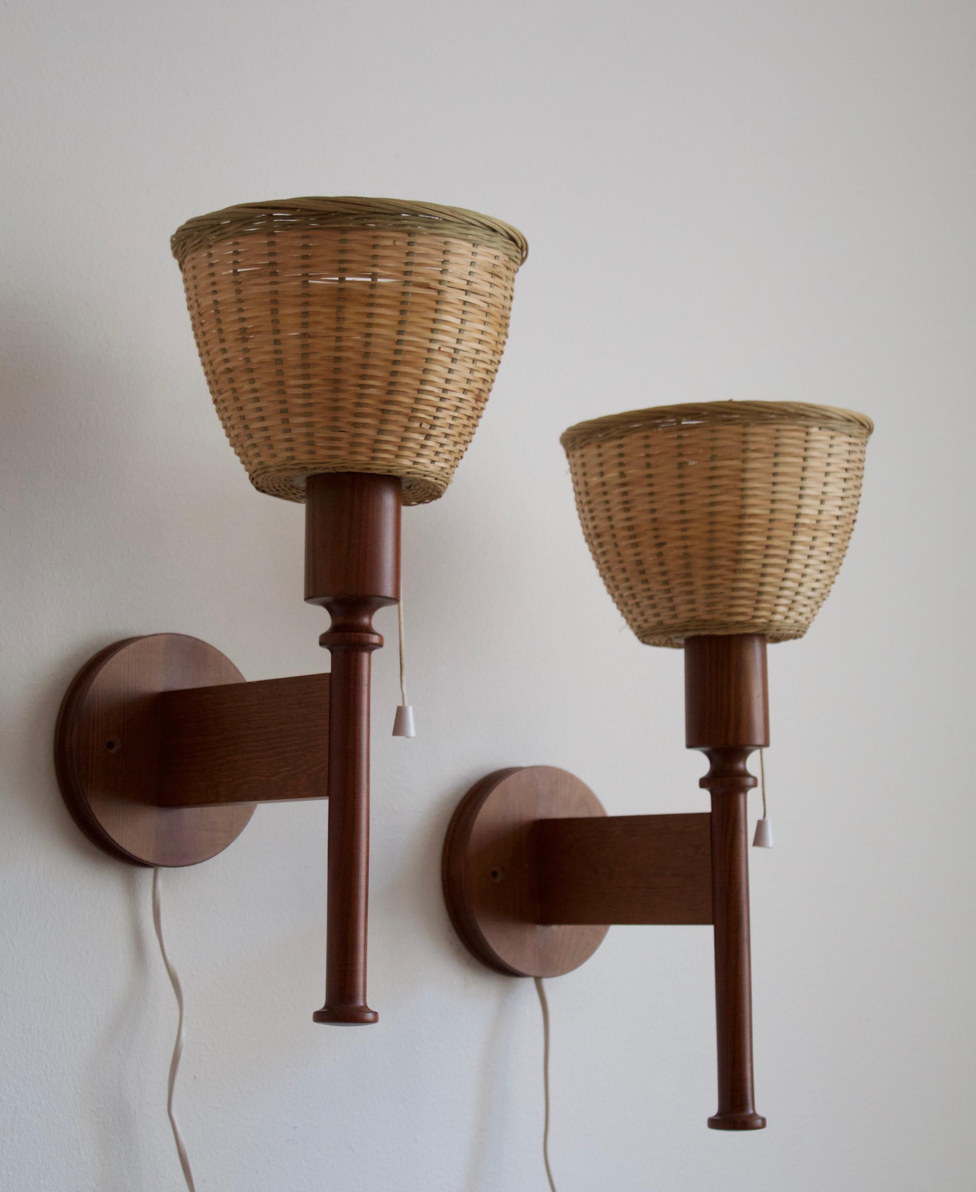 A set of sculptural solid dark-stained pine wall lights / sconces. Designed by Uno Kristiansson, for Luxus, Sweden, 1960s. Assorted vintage rattan lampshades.

Other designers of the period include Axel Einar Hjorth, Roland Wilhelmsson, Charlotte