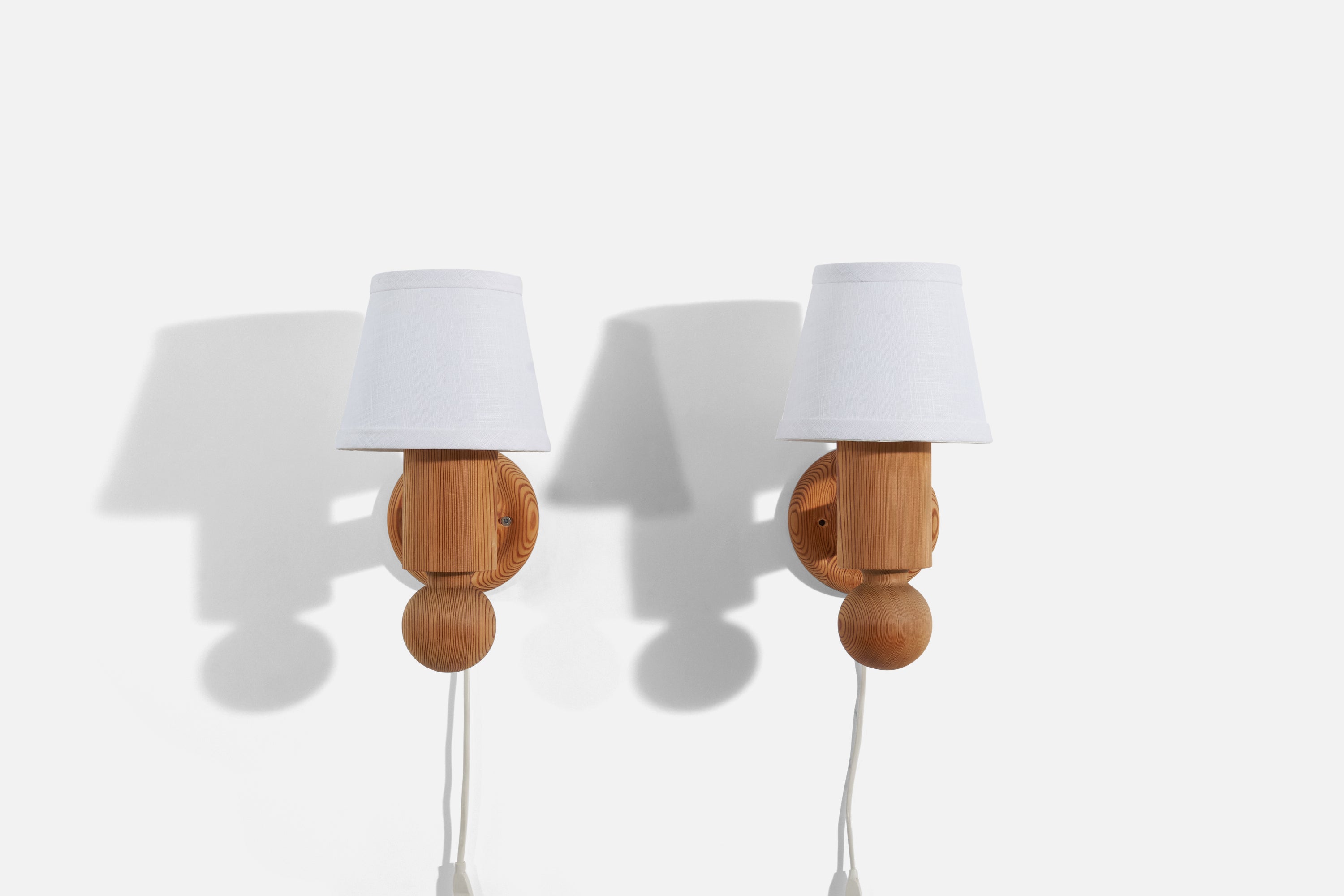 A pair of pine and fabric wall lights designed by Uno Kristiansson and produced by Luxus Vittsjö, Sweden, 1960s.

Dimensions of Sconce (inches) : 6.875 x 4.75 x 7 (H x W x D)
Dimensions of Shade (inches) : 4 x 6 x 5 (T x B x H)
Dimensions of