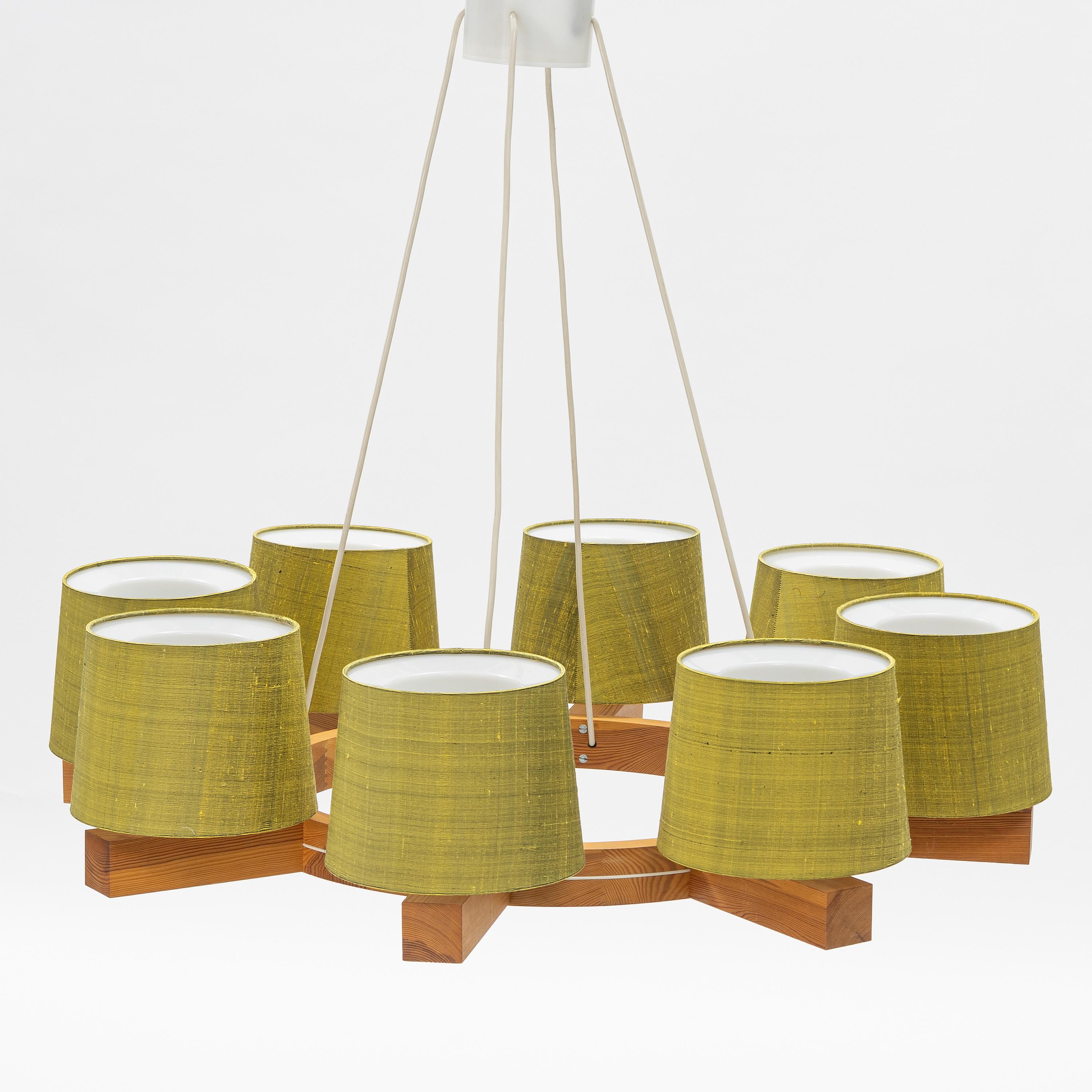 Designed by Uno & Östen Kristiansson in the 1960s in Sweden for Luxus, Vittsjö.
A pine wood ring with eight arms and yellow-green Texolux shades. 
Diameter 96, height 84 cm.
