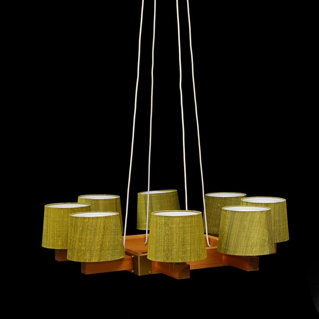 Designed by Uno & Östen Kristiansson in the 1960s in Sweden for Luxus, Vittsjö.
A pine wood frame with eight arms and green Thai-Silk Texolux shades. 
Diameter 90, height 85 cm.