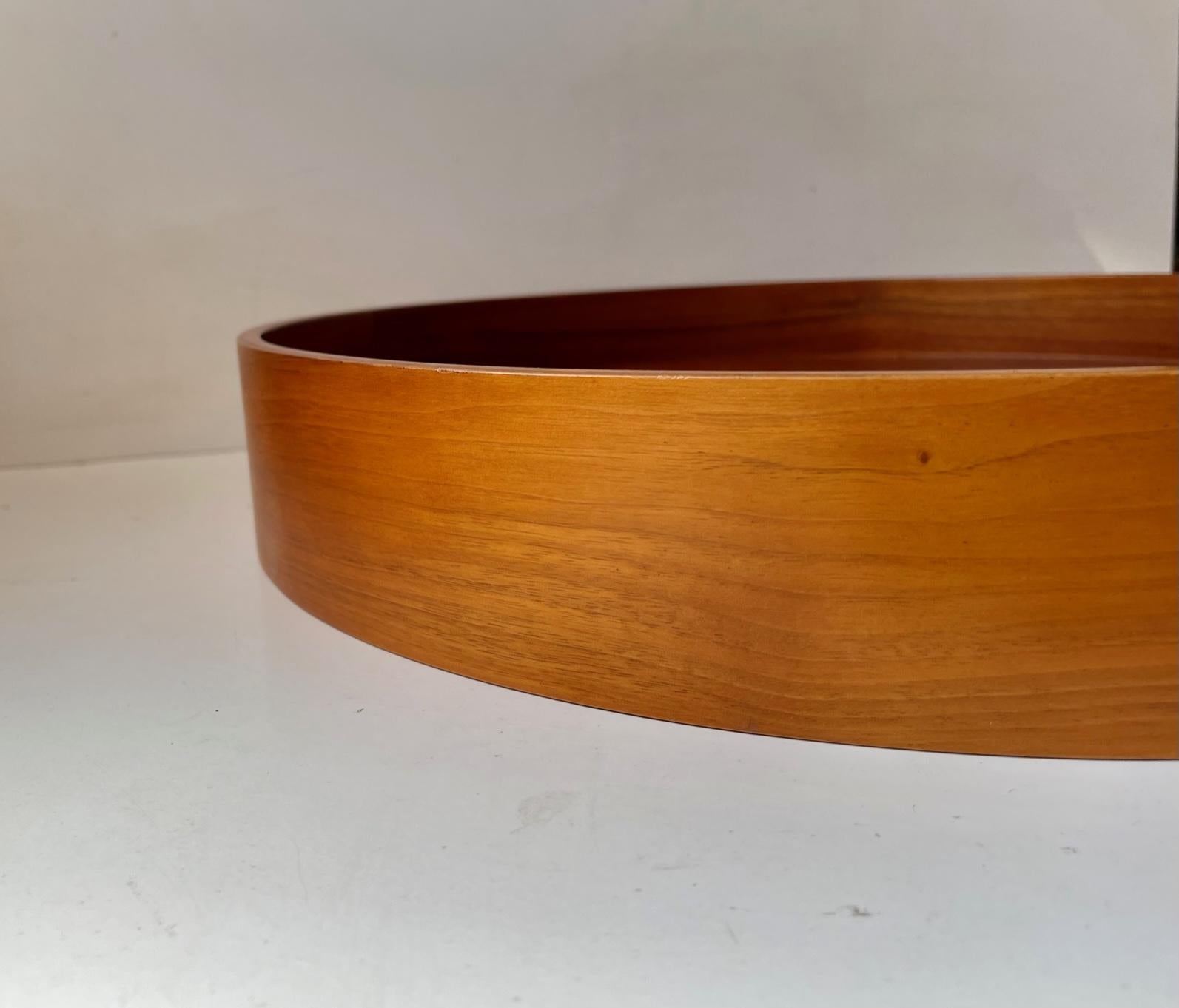 A beautifully crafted large round tray in form-pressed teak assembled without the use of metal. It has two useable sides. A side with high edge and a side with a more shallow edge. It was made in Sweden during the 1960s and the design is attributed