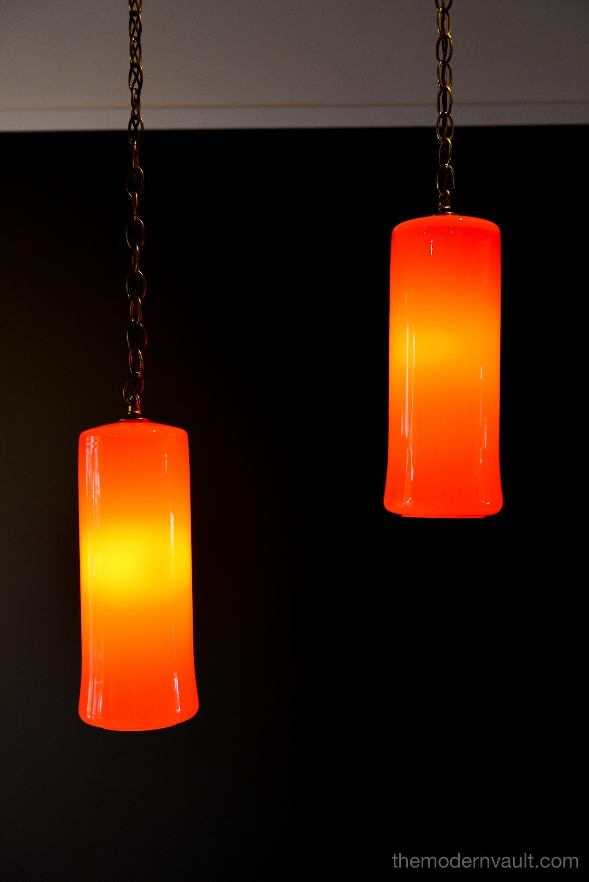 Uno & Östen Kristiansson for Luxus orange glass pendant lights, circa 1960. Beautiful deep orange colored blown glass pendant swag lights with original chain and wiring. Lights can be kept original as a plug in as shown, or you can easily separate