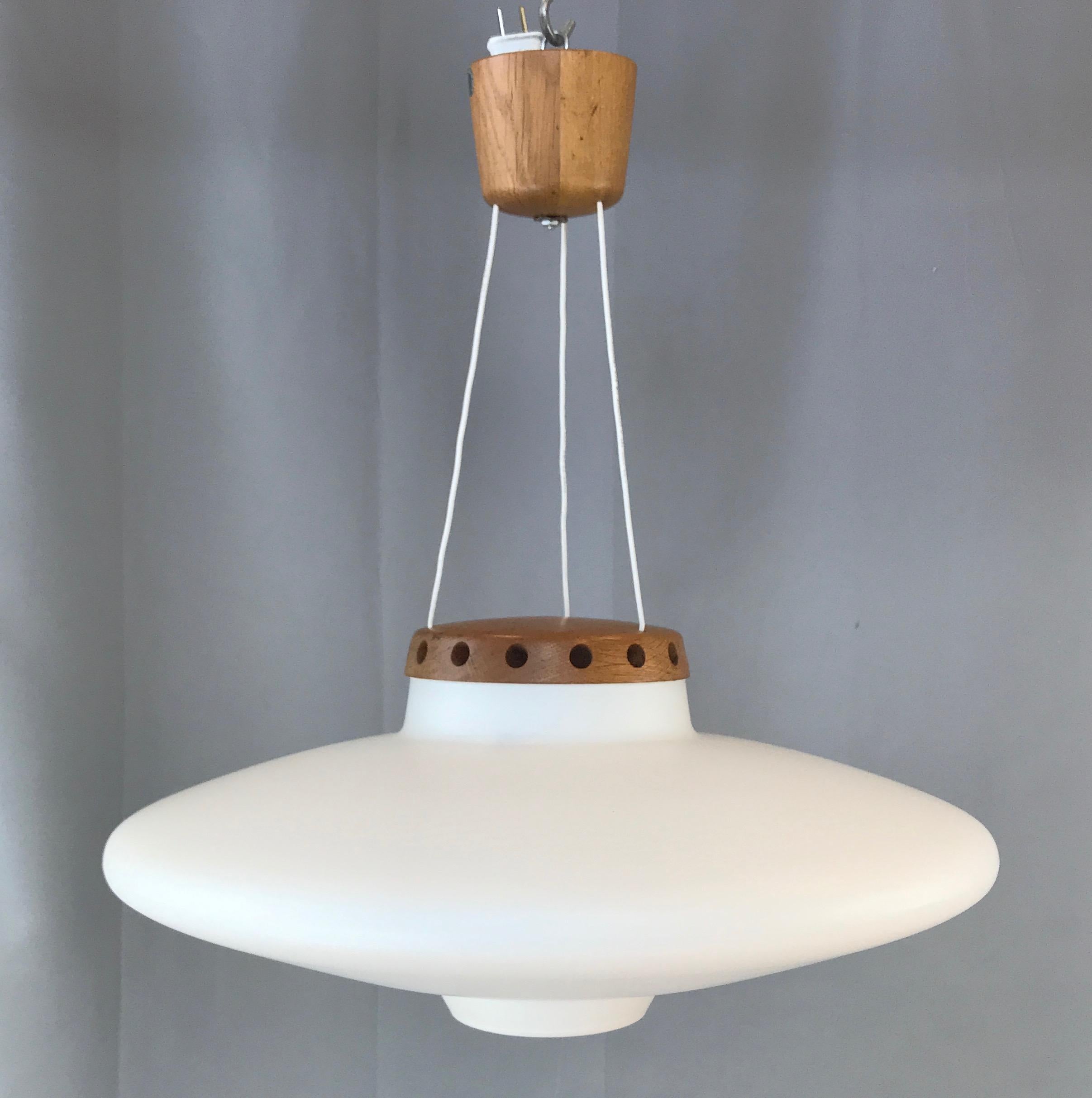 Eine skandinavisch-moderne Teakholz-Pendelleuchte aus den 1950er Jahren & aus mattiertem Opalglas von Uno & Östen Kristiansson für Luxus. 

Scarce Design hat eine absolut fantastische:: archetypische UFO-Ästhetik. Großer Schirm aus gefrostetem