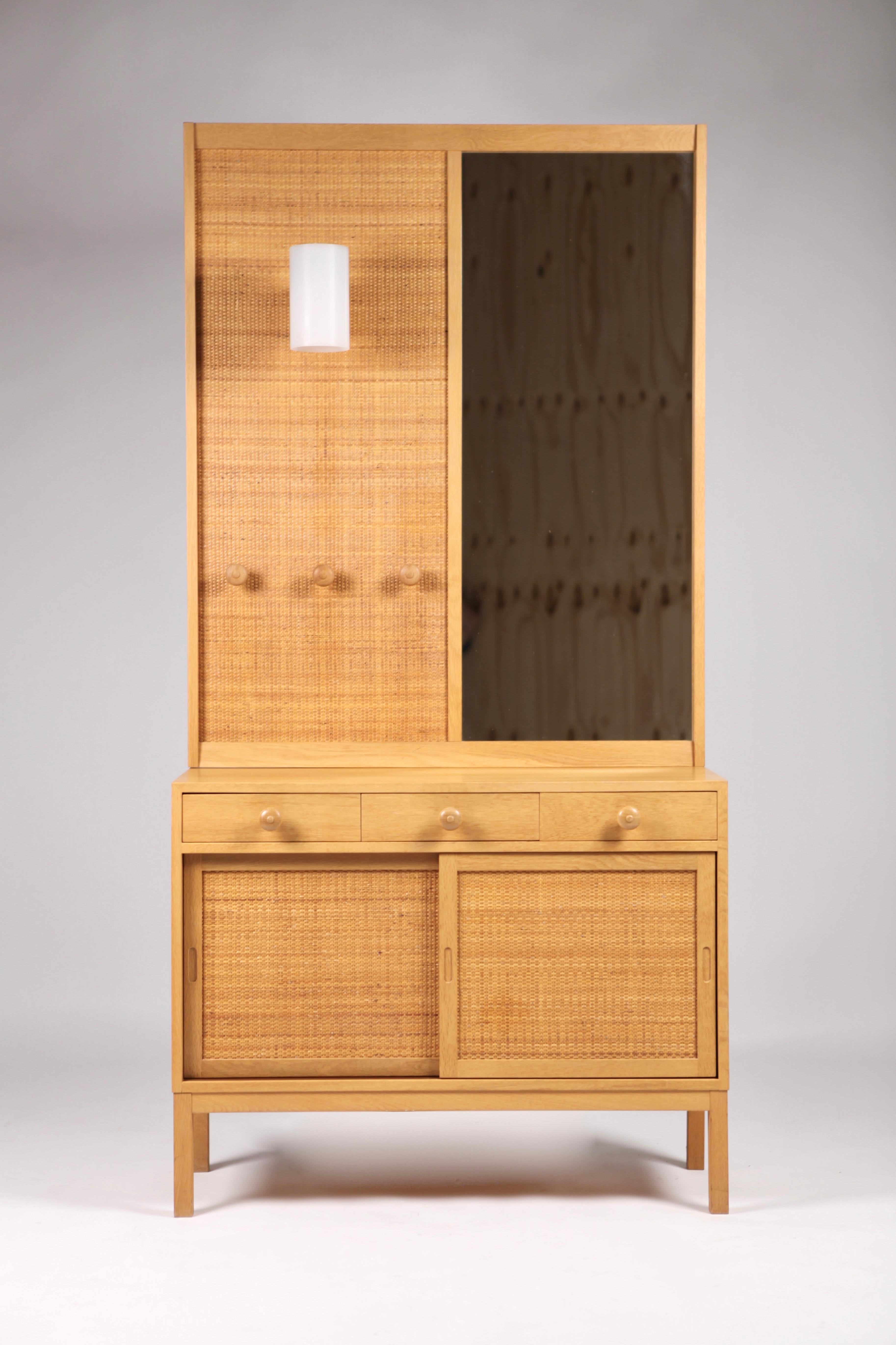 Uno & Östen Kristiansson, arcón con espejo de pared, 2 piezas. Realizado en roble y caña por la empresa sueca de muebles Luxus Vittsjö en Suecia en la década de 1960. El espejo con aplique montado.
3 estantes y puertas correderas de caña.
Firmado