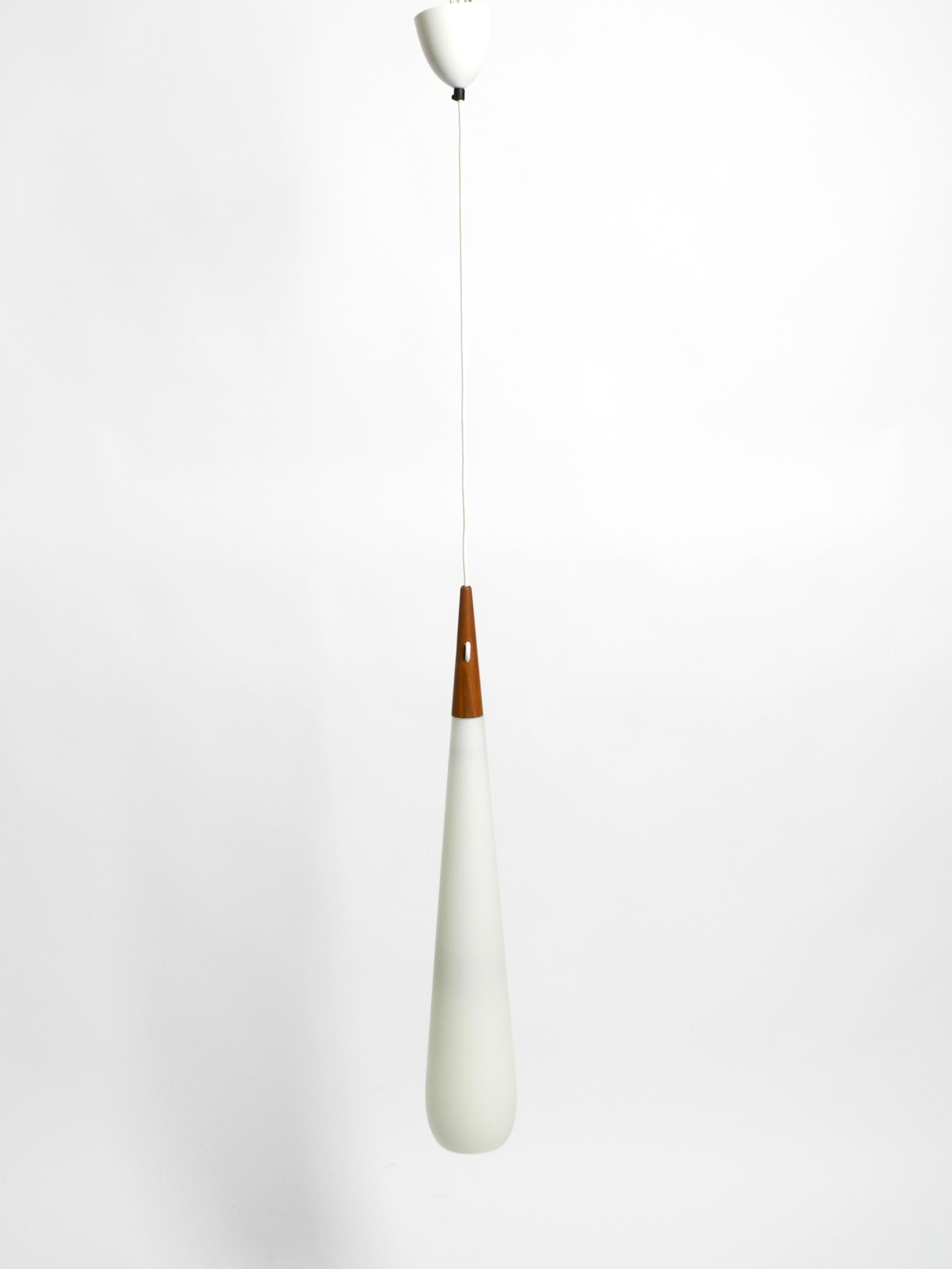 Belle et très rare lampe à suspension longue en teck et verre opale, conçue en 1957 par Uno & Östen Kristiansson. Fabriqué par Luxus Vittsjö, Suède.
Superbe design scandinave minimaliste. Crée une lumière très agréable.
L'abat-jour est en verre
