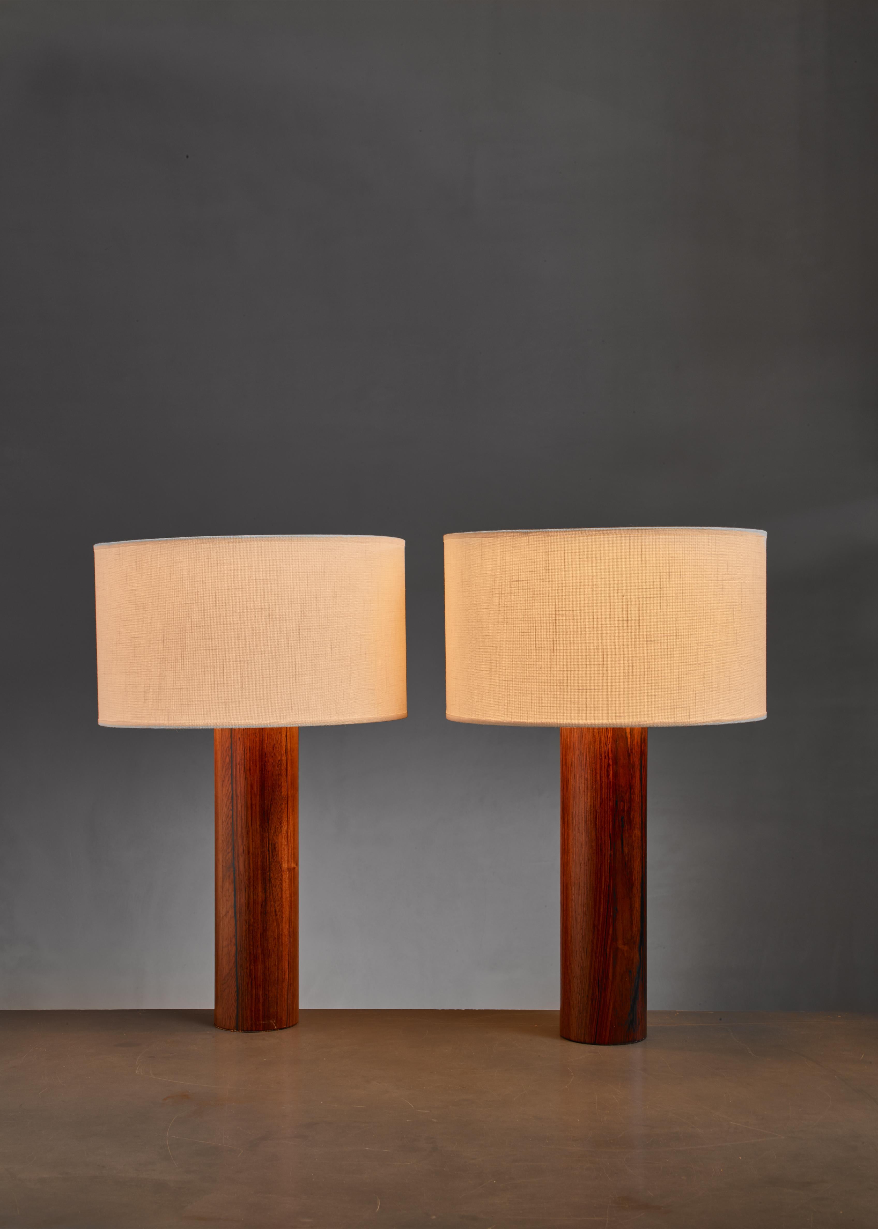 A pair of cylindrical, wooden table lamps by Uno & Östen Kristiansson for Luxus. 

Labeled by Luxus. The measurements stated are of the lamps without the fabric shade.
Base height excl. lamp holder: 36 cm / 14.17 inch
Shade dimensions are: