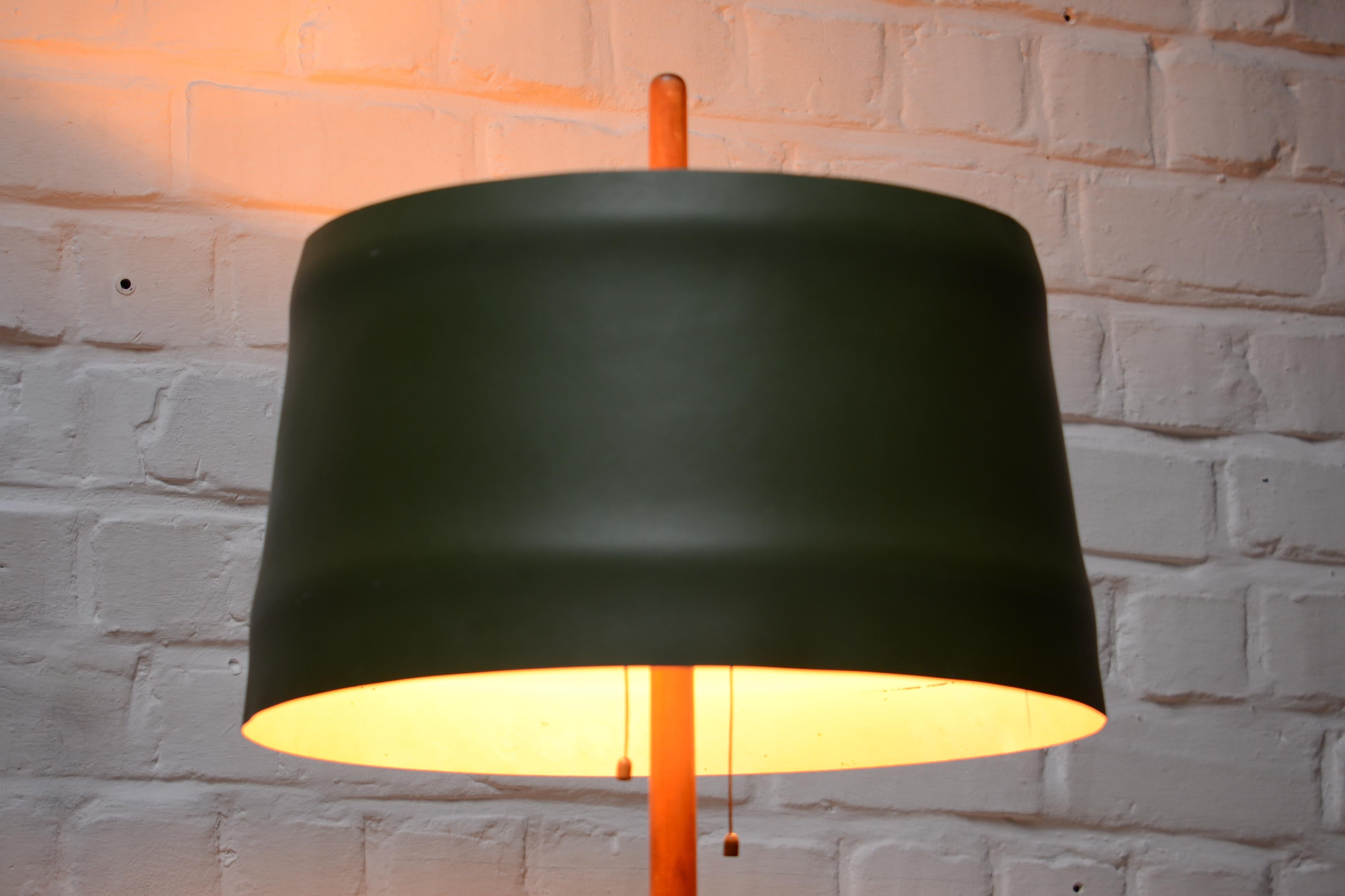 Teak and green leather floor lamp by Uno & Osten Kristiansson. The shade is made of green leather over a white painted frame. On top you can see a part of the teak tubular frame. Two bubble light with two cords of leather to turn them on or off.