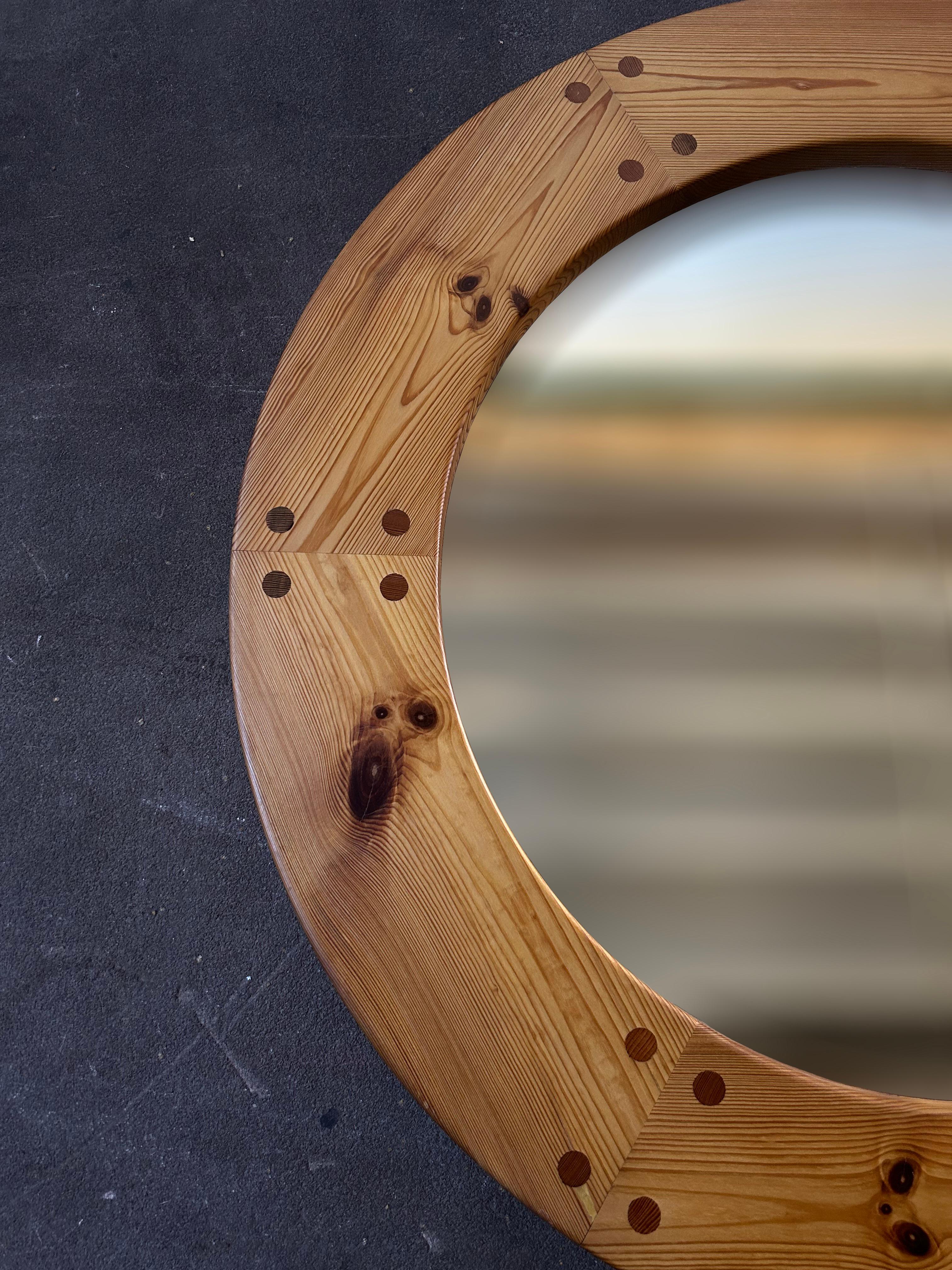 Decorative round wall mirror in solid pine with decorative visible round wooden dowels designed by Swedish designers Uno & Östen Kristiansson and manufactured by Luxus Vittsjö in Sweden in the 1960’s.
The mirror is the perfect detail for any style