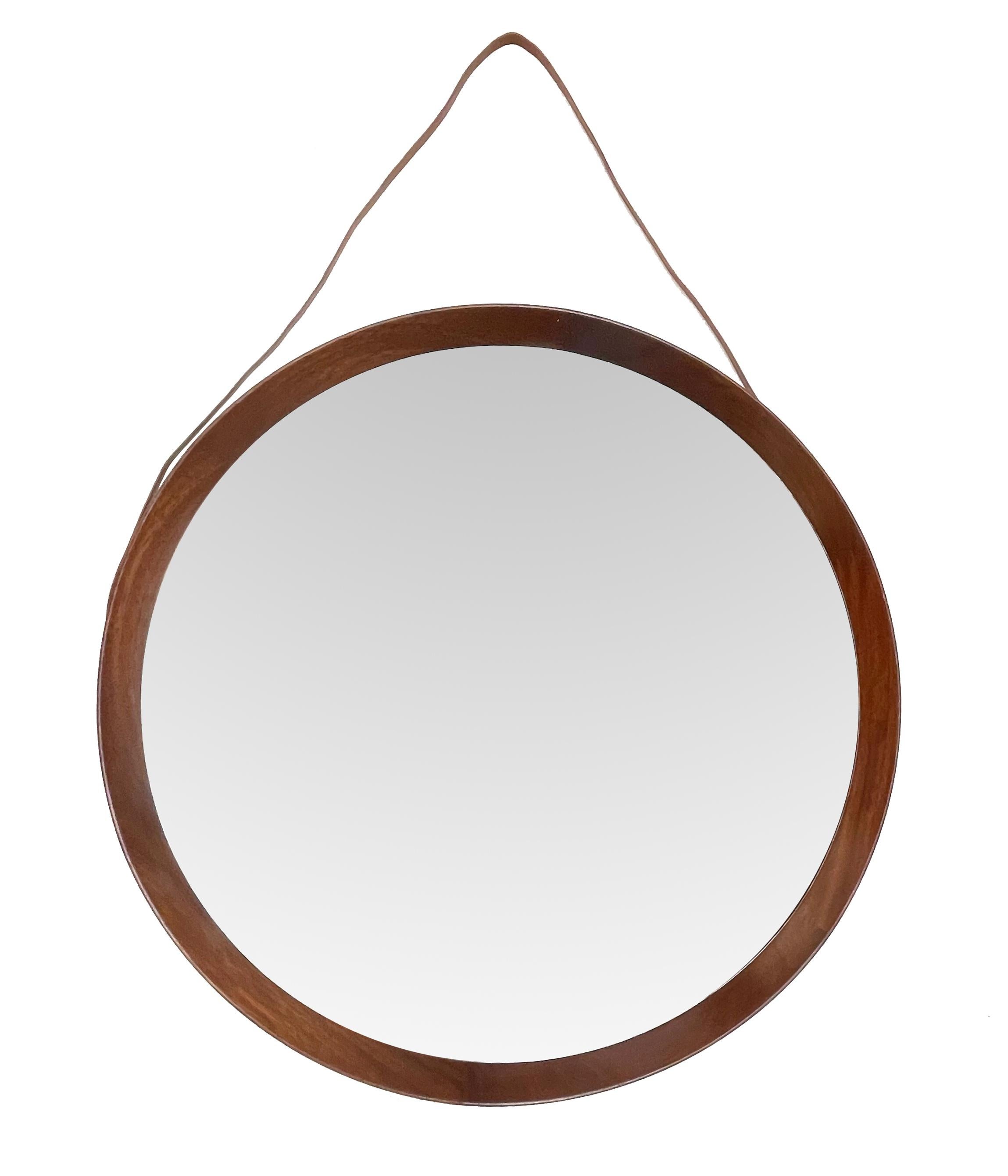 Amazing midcentury in teak with a leather hanging strap wall mirror. This astonishing item was designed by Uno & Östen Kristiansson for a Luxus production during the 1960s. 

The frame circulates the glass and is made out of different pieces of