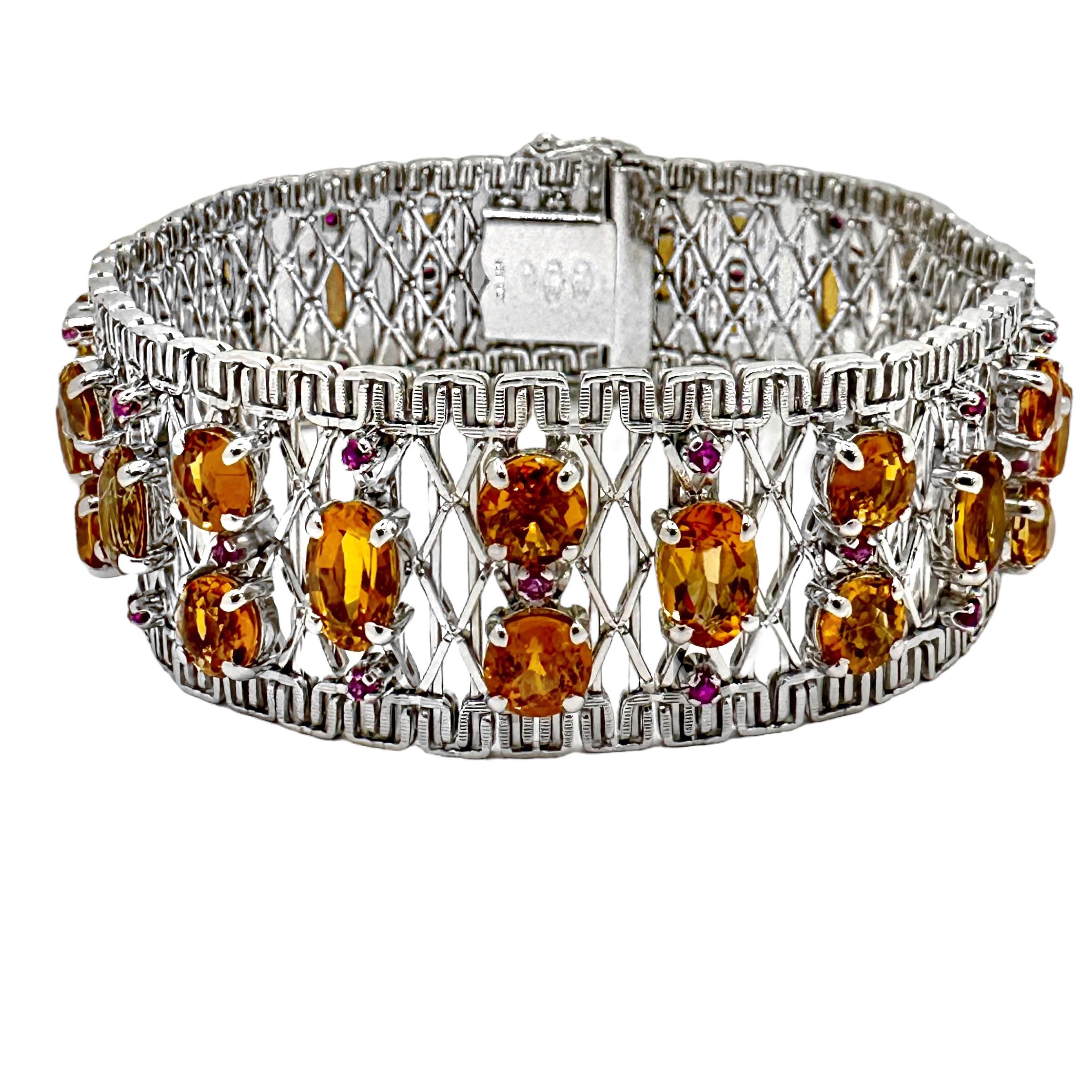 Sorprendente brazalete de oro blanco de 18 quilates de Unoaerre, engastado con 34 topacios imperiales de talla brillante, ovalados y redondos, acentuados con 30 rubíes de talla redonda. La combinación de colores está engastada sobre un entramado de