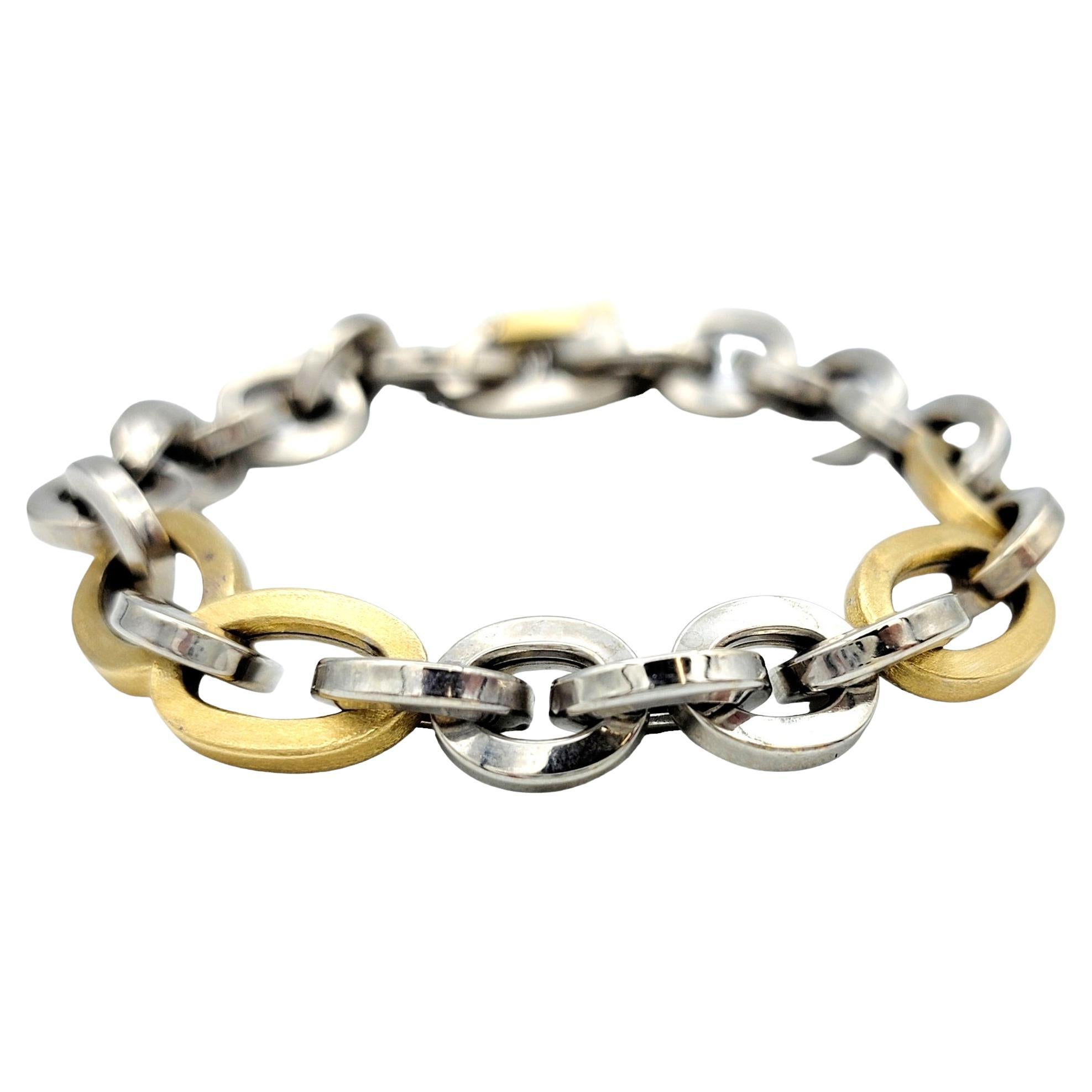 This opulent Unoaerre chain bracelet stands as a testament to bold elegance with its large, chunky links crafted in luxurious 18 karat gold. The striking design features an arresting contrast between gleaming yellow gold links and the cool,