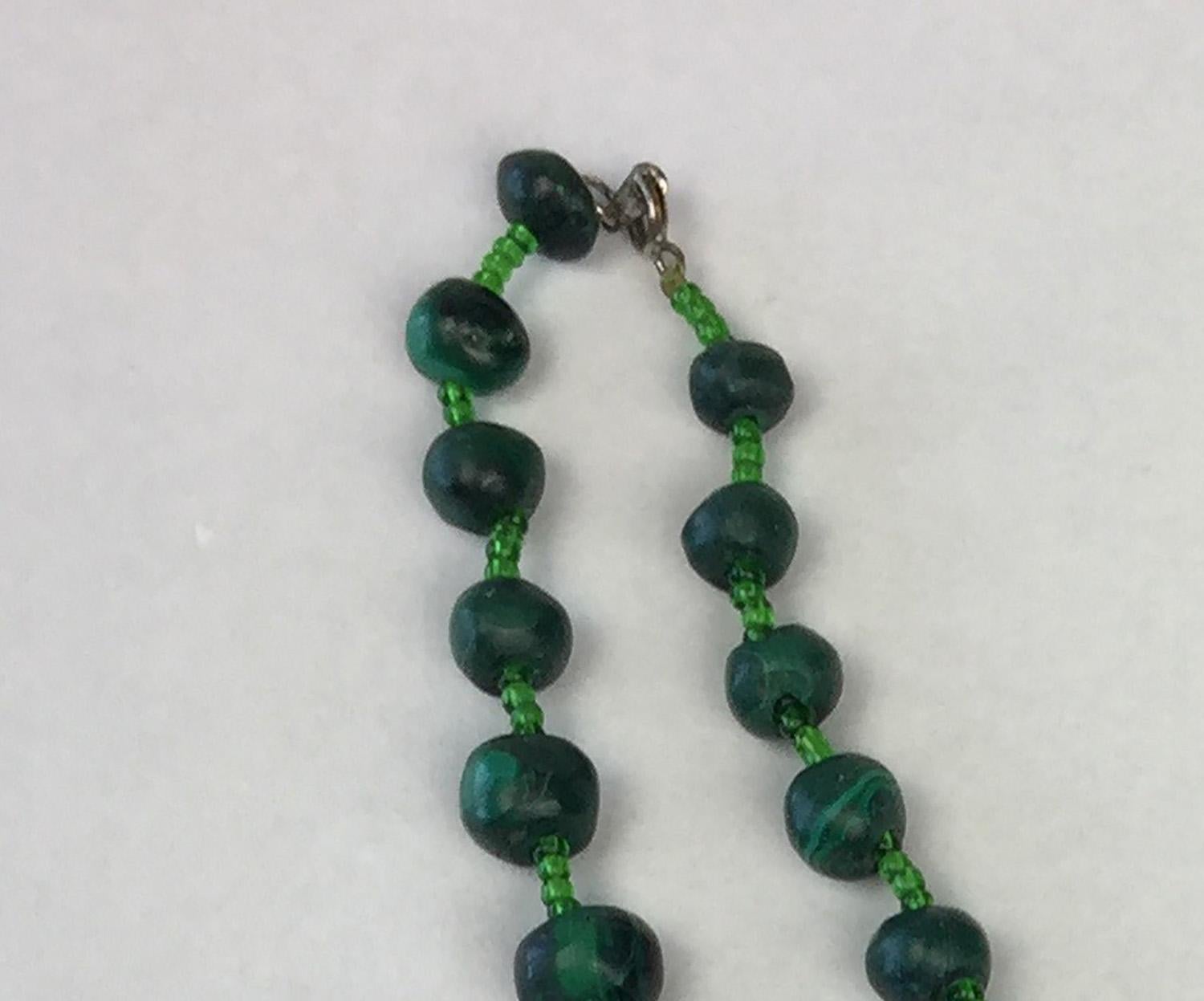 Unpolished Malachite necklace with glass beads in-between main beads with snap clasp.