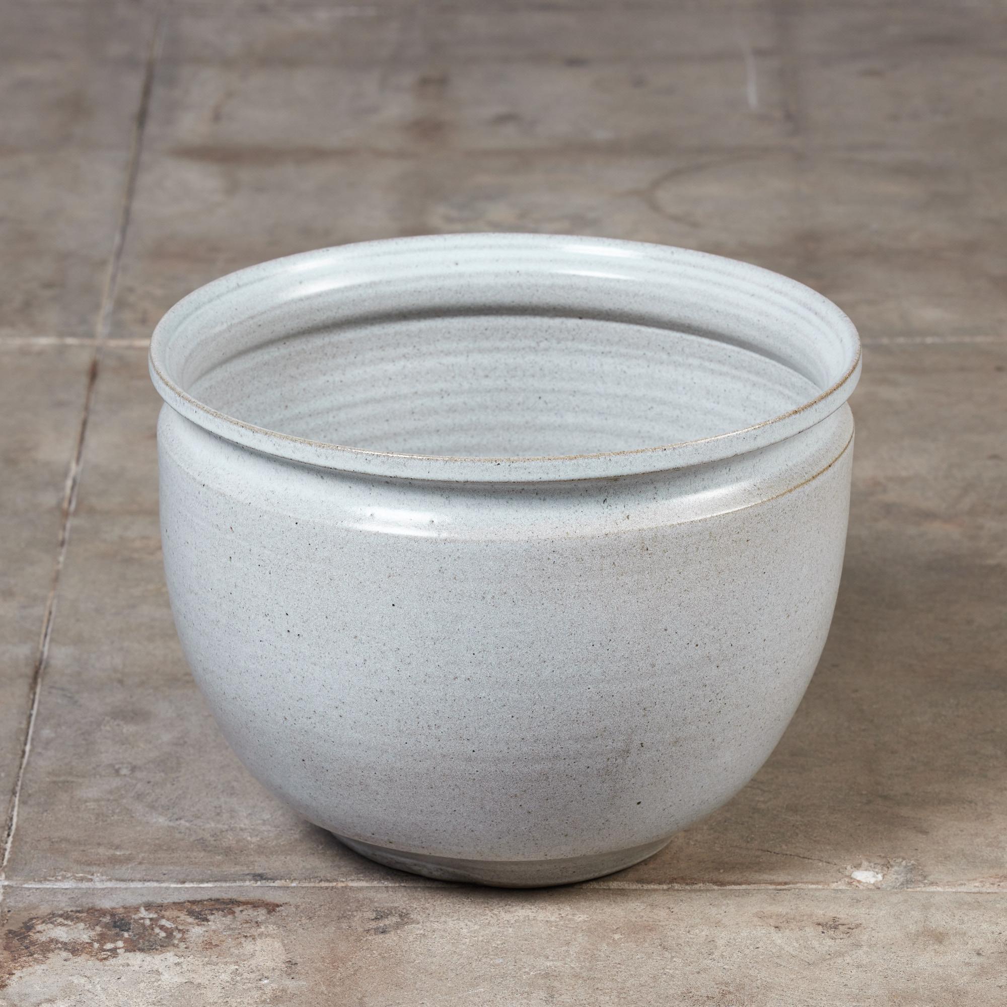 A modest bowl planter with a thin lip and gently curved bowl shape from Robert Maxwell and David Cressey’s 1970s collaboration, Earthgender. This example has a translucent white glaze. We have two planters available and the listed price is per