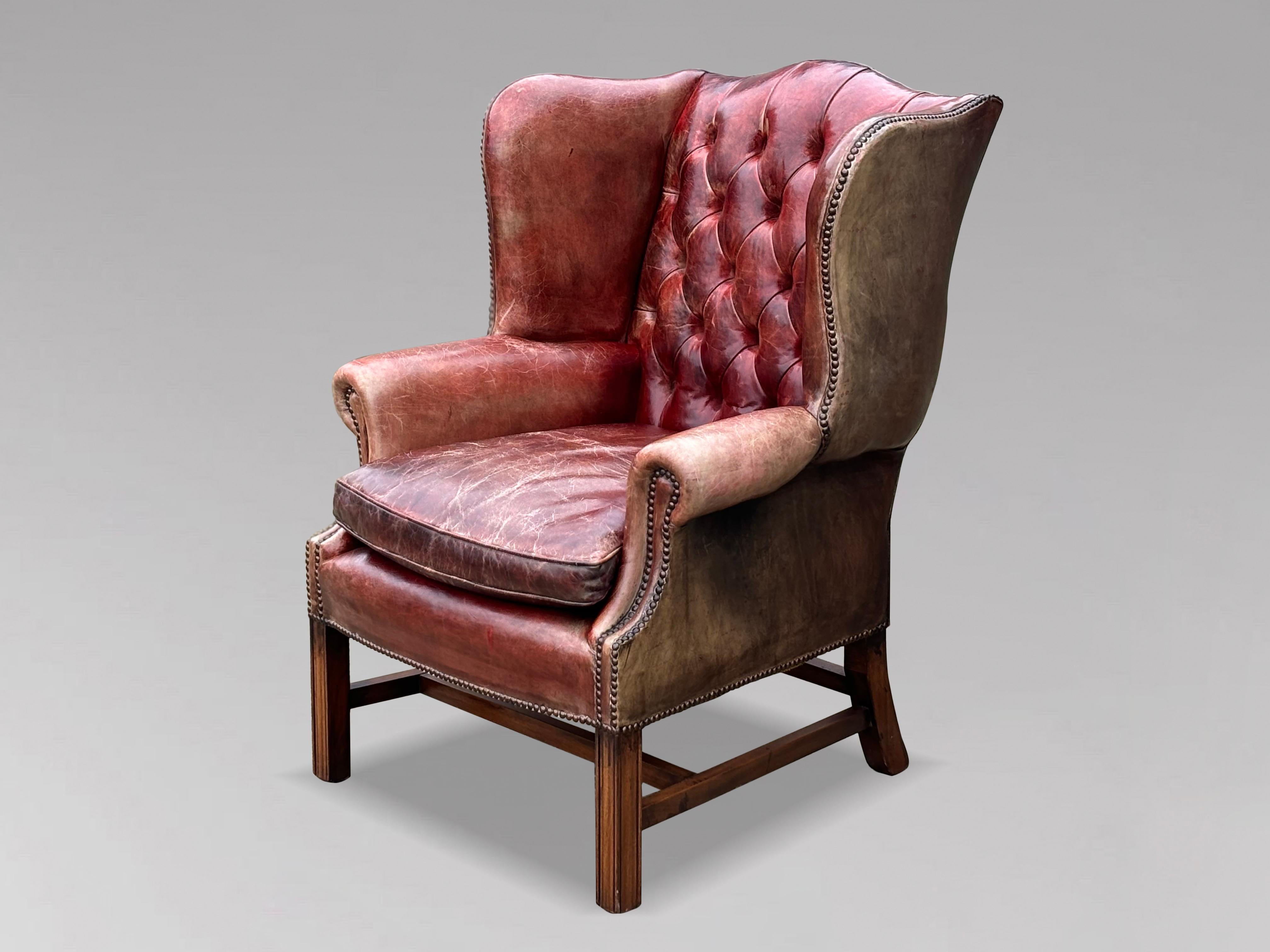 A high-quality, untouched 19th-century burgundy red leather full-button wing armchair in the George III style. The substantial, well-shaped frame features a deep-buttoned upholstered back, and arms, all covered in the original burgundy red leather.