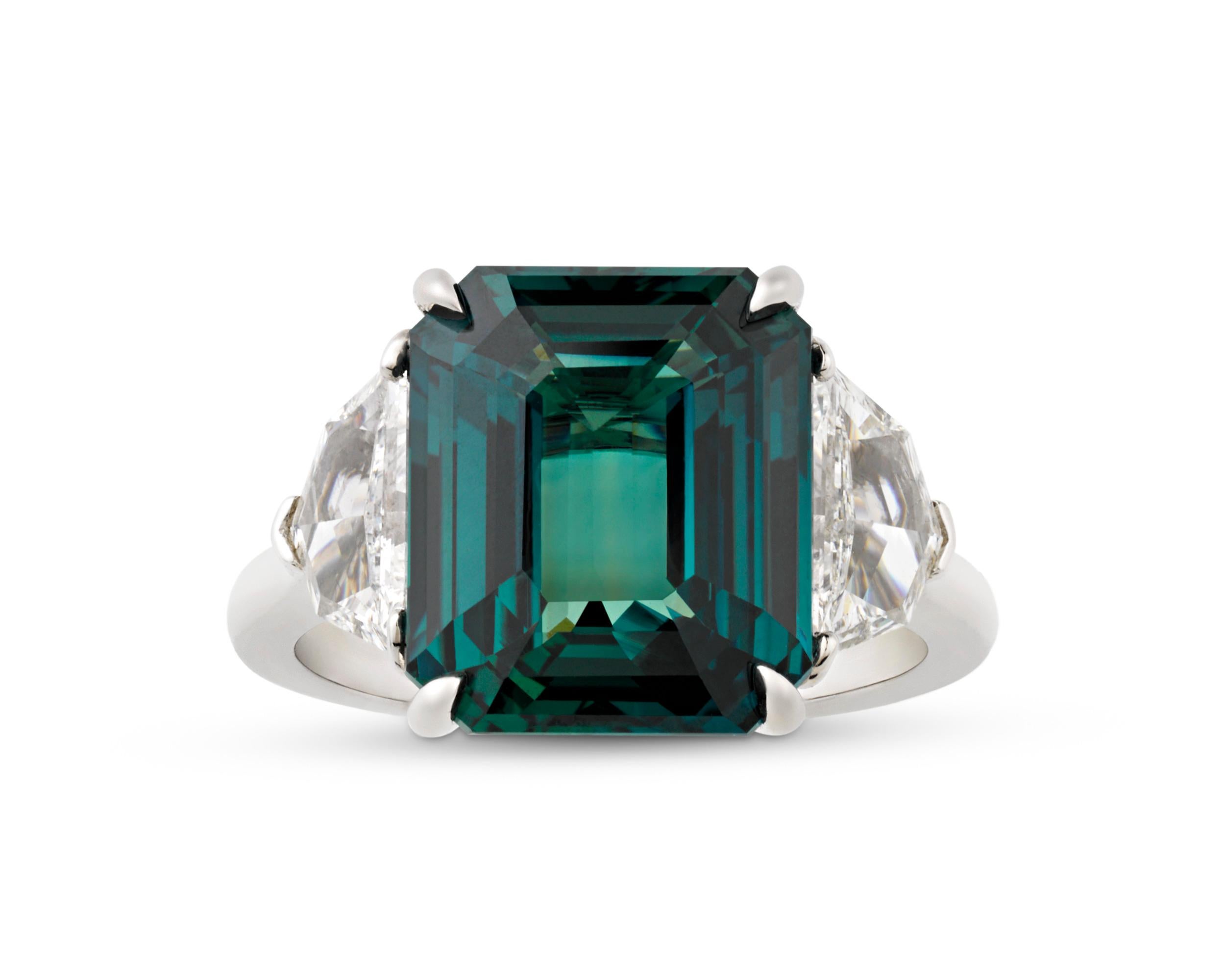 An untreated bluish-green sapphire weighing 8.03 carats centers this dazzling ring. The fancy color sapphire is certified by both the Gemological Institute of America and C. Dunaigre as untreated and of Ceylon origin. With its stunning beauty and