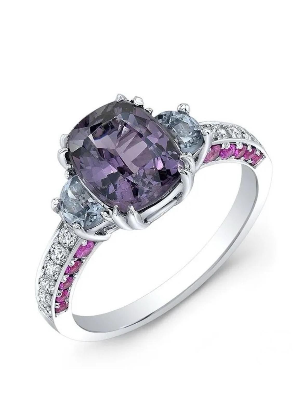 18K white gold ring, featuring an untreated 2.21 carat Purple Spinel, complemented by two untreated half-moon cut Violet Spinels totaling 0.62 carats. These gorgeous gems are surrounded by 20 Ceylon Pink Sapphires totaling 0.52 carats and numerous