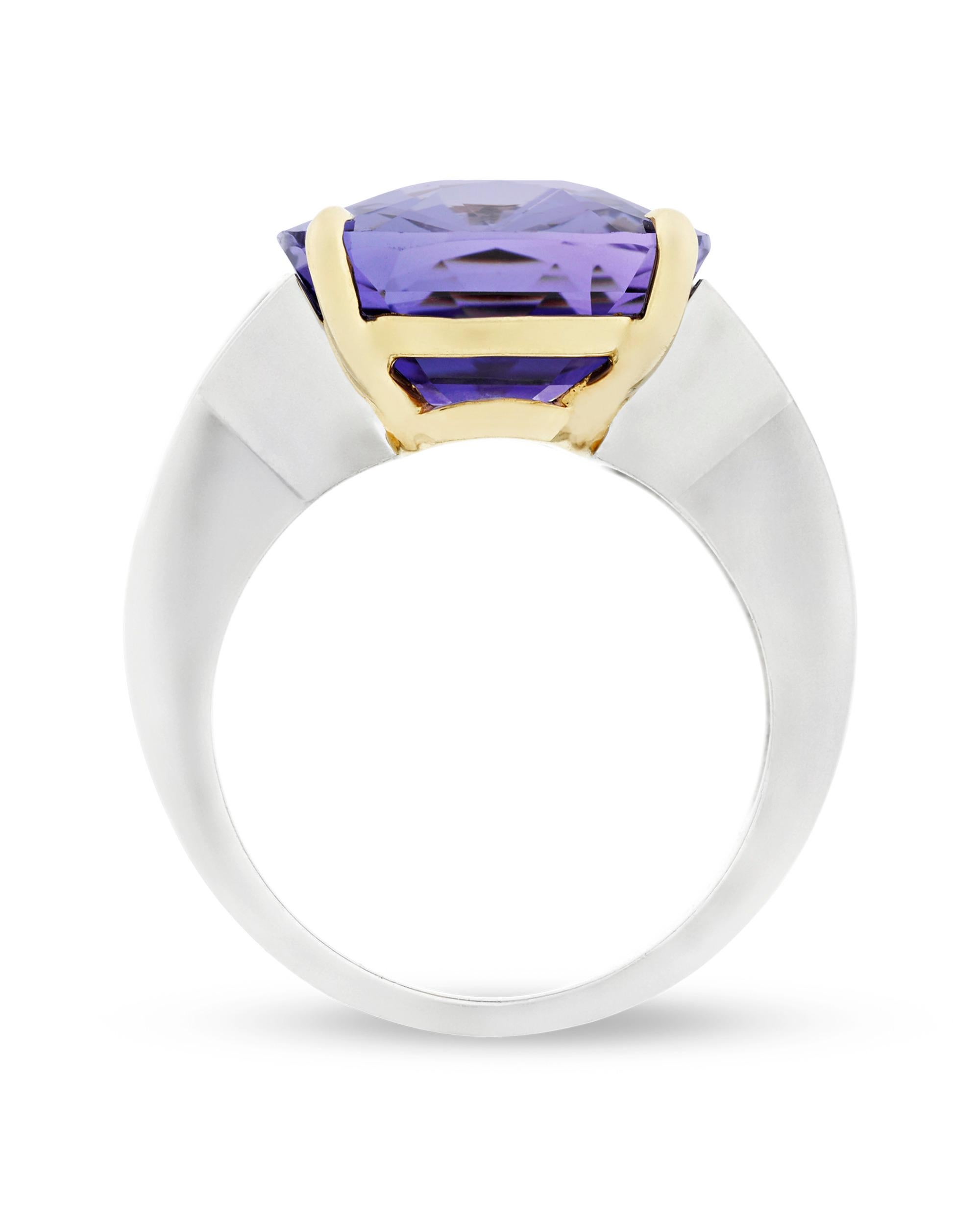A brilliant 13.58-carat lavender sapphire radiates at the center of this classically stunning ring. The step-cut gem is set in a sophisticated platinum and 18k yellow gold setting between glistening diamonds totaling 1.40 carats. Both dramatic and