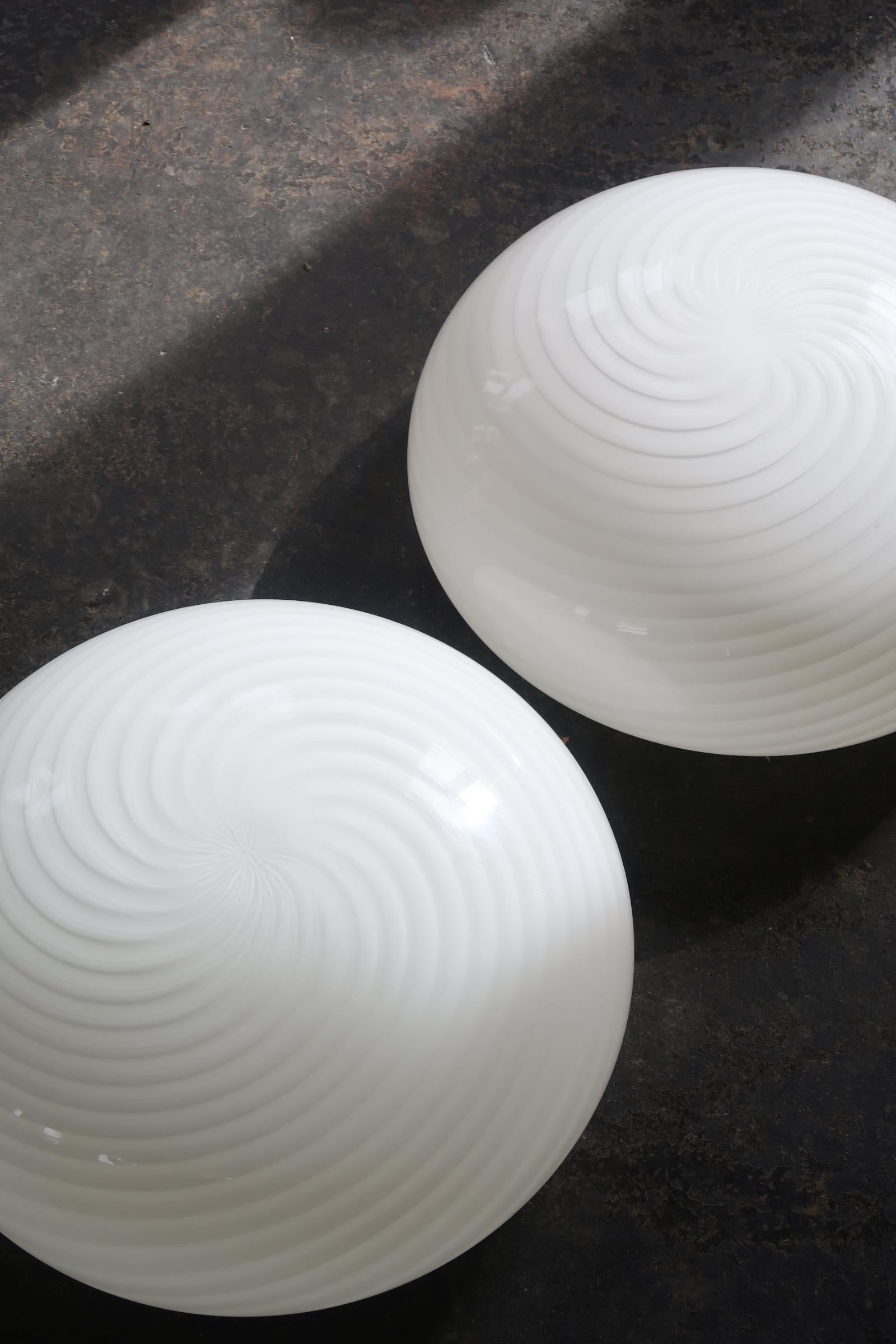 Several pieces available 
Unused (new) vintage Murano glass ceiling lamp with white swirl pattern. Can be used both as a ceiling lamp or as a wall lamp. 2x E27 socket. Handmade in Italy, 1970s, and comes with a new white metal backplate.
D: 36 cm H: