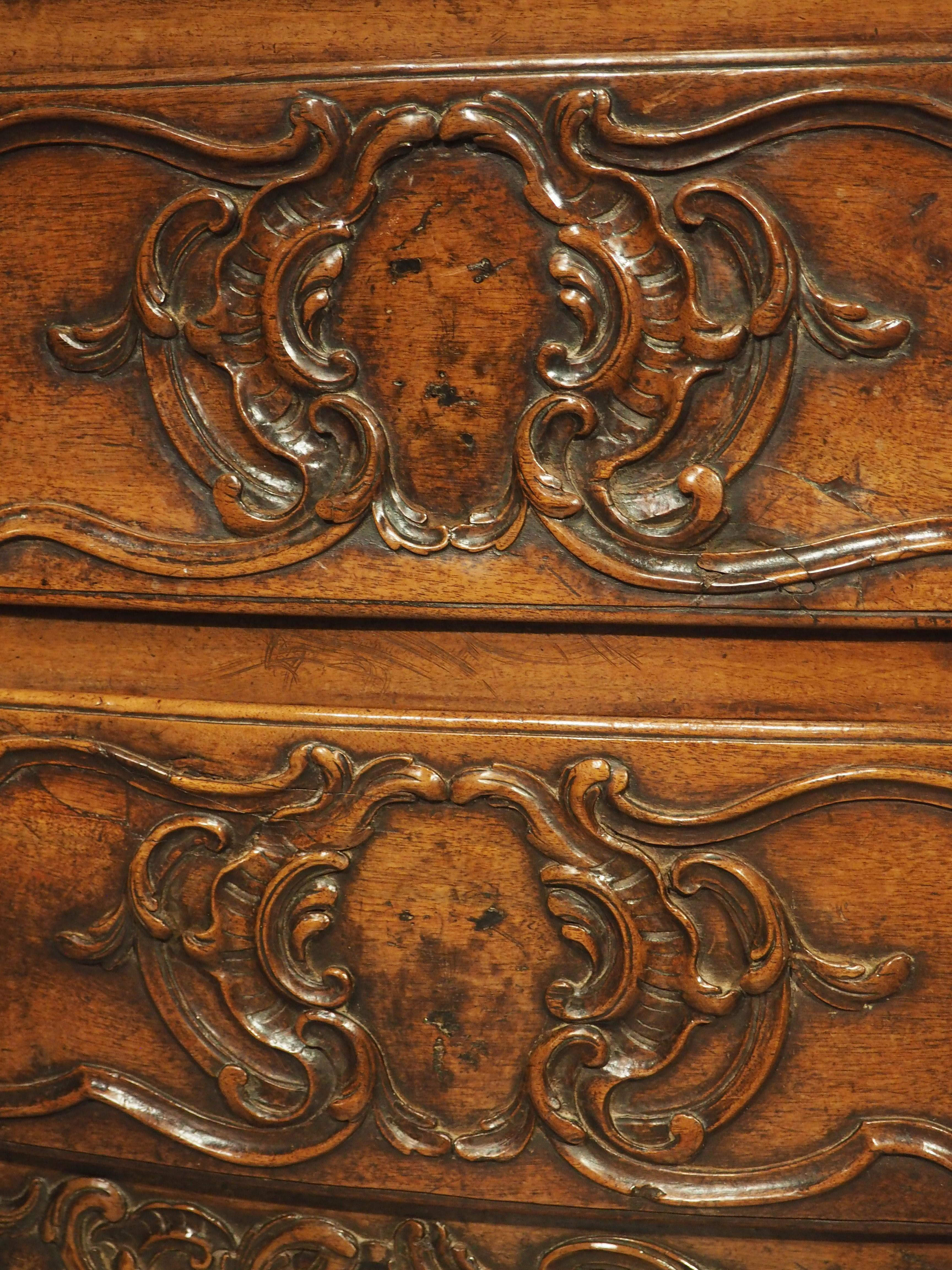 Featuring Rococo elements from the period of Louis XV, this walnut commode was hand-carved in Arles, France, during the 18th century. The chest of drawers is quite unusual in that it is only 36 inches wide, and the facades have subtle curves,