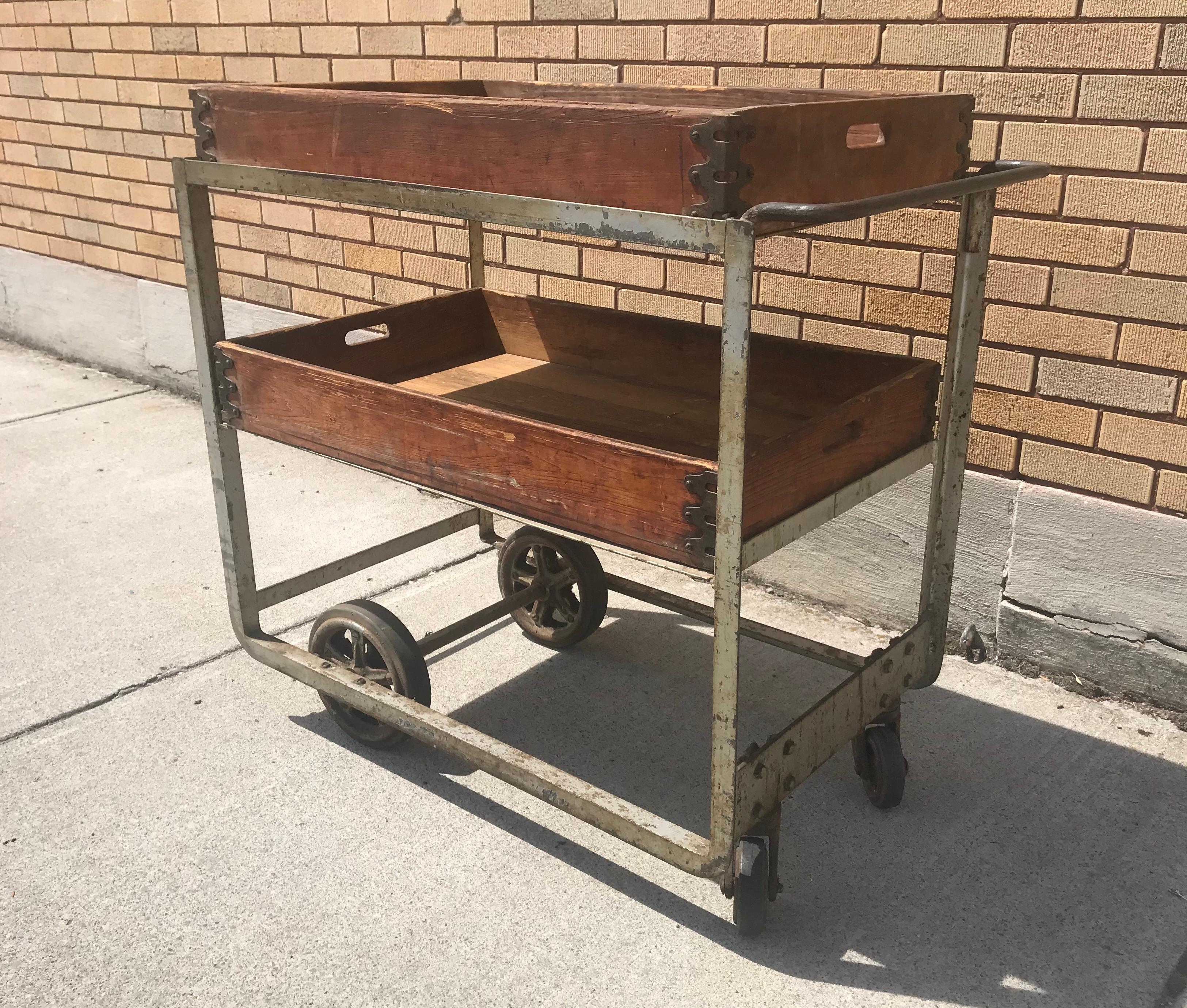 Unusual 1920s industrial cast iron and wood bar cart / trolly, Nutting Truck Co, Wonderful industrial design. Solid cast iron frame, two removable wood shelves, trays with amazing corner details. Recently purchased from prominent private gentleman's