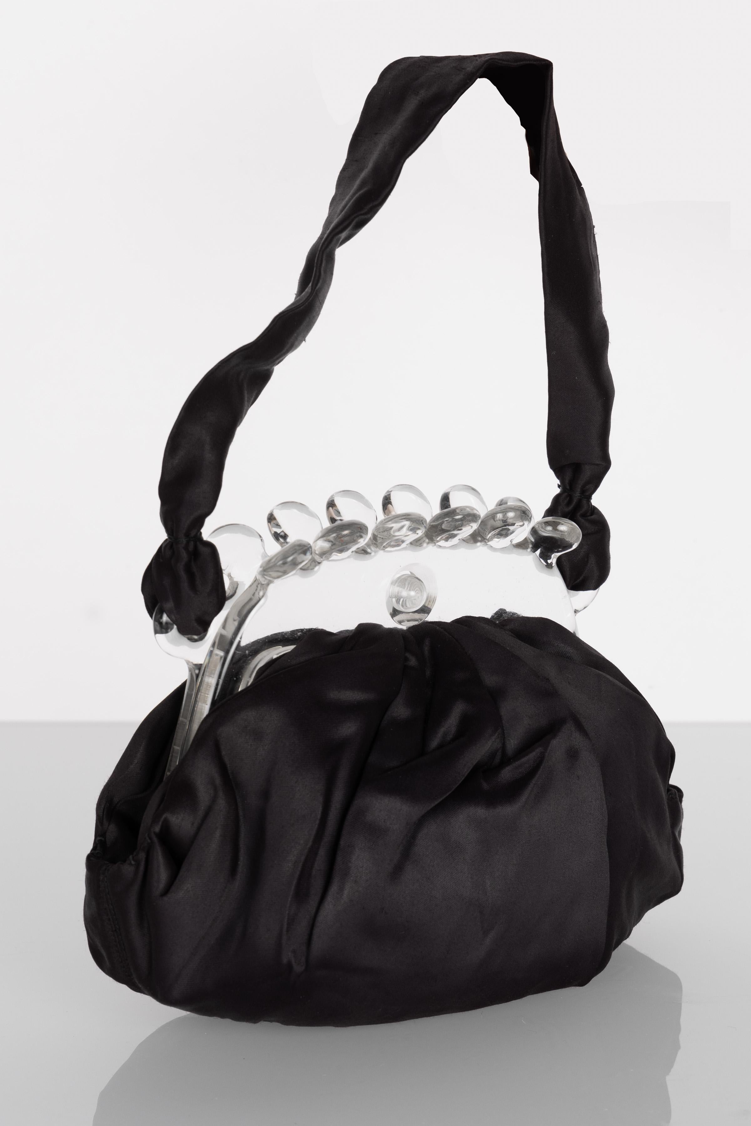 From the 1920s, this unusual evening clutch is elegant and timeless at once. Done in black satin with black satin handles, it has a fabulous, ruffled, clear Lucite standup frame that is thick and sturdy. The black satin is pleated where it meets the