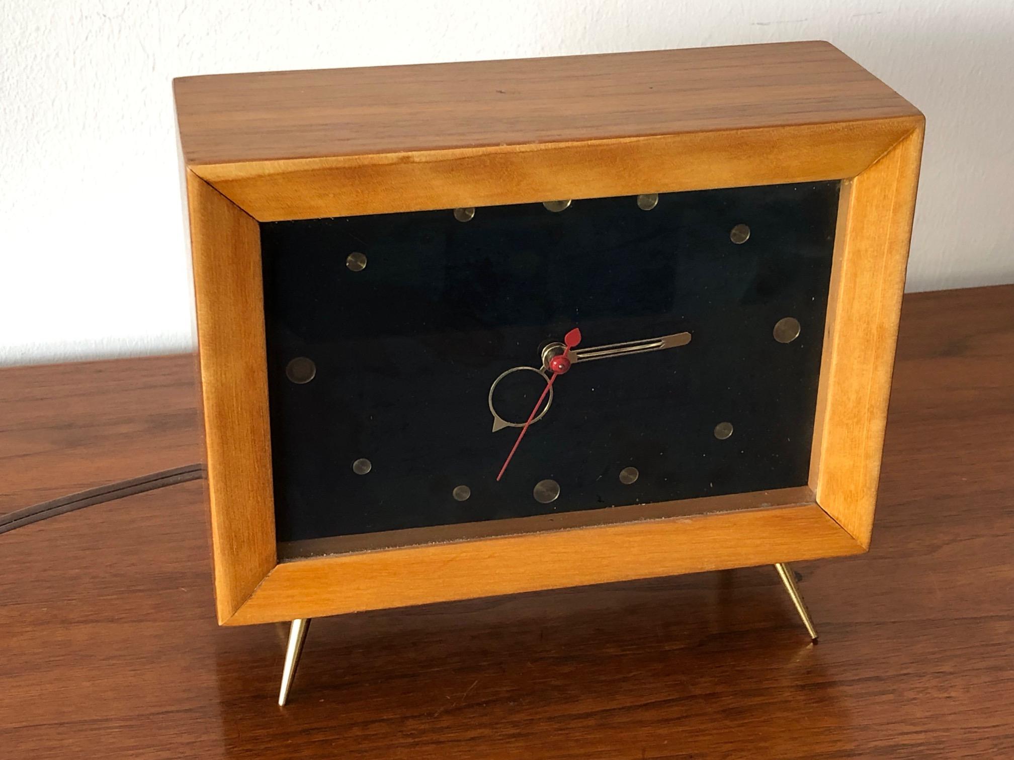 An unusual 1950s table clock, shaped like a TV. Great 1950s look in the style of Howard Miller. Case in walnut with brass angled legs.