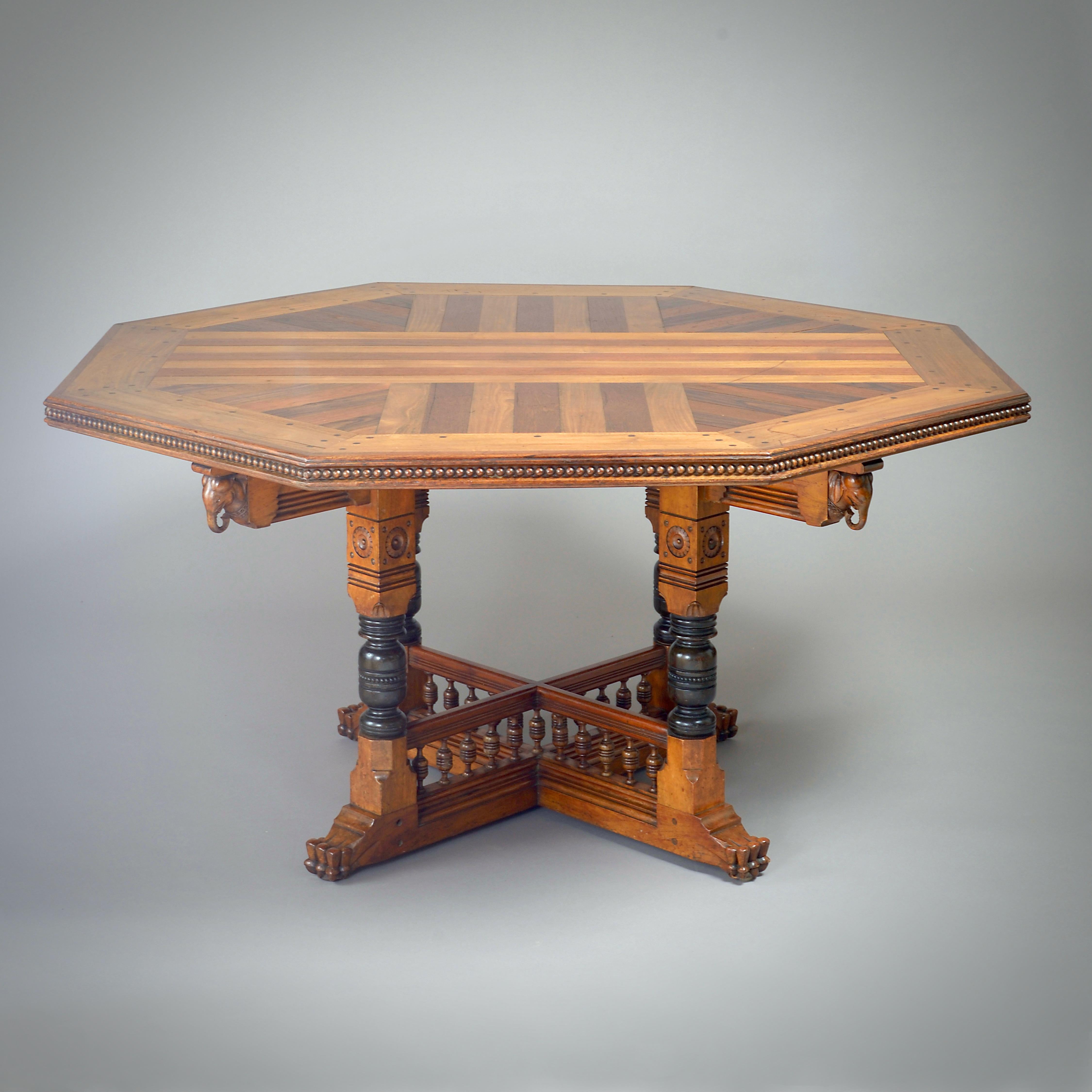 TABLE CENTRALE OCTOGONALE TRÈS INHABITUELLE EN BOIS DE SATIN, TECK ET BOIS DE ROSE NOIR, VERS 1880.

De construction chevillée. Le plateau est en parquet, la base cruciforme partiellement ébonisée est sculptée de têtes d'éléphants et de pieds en