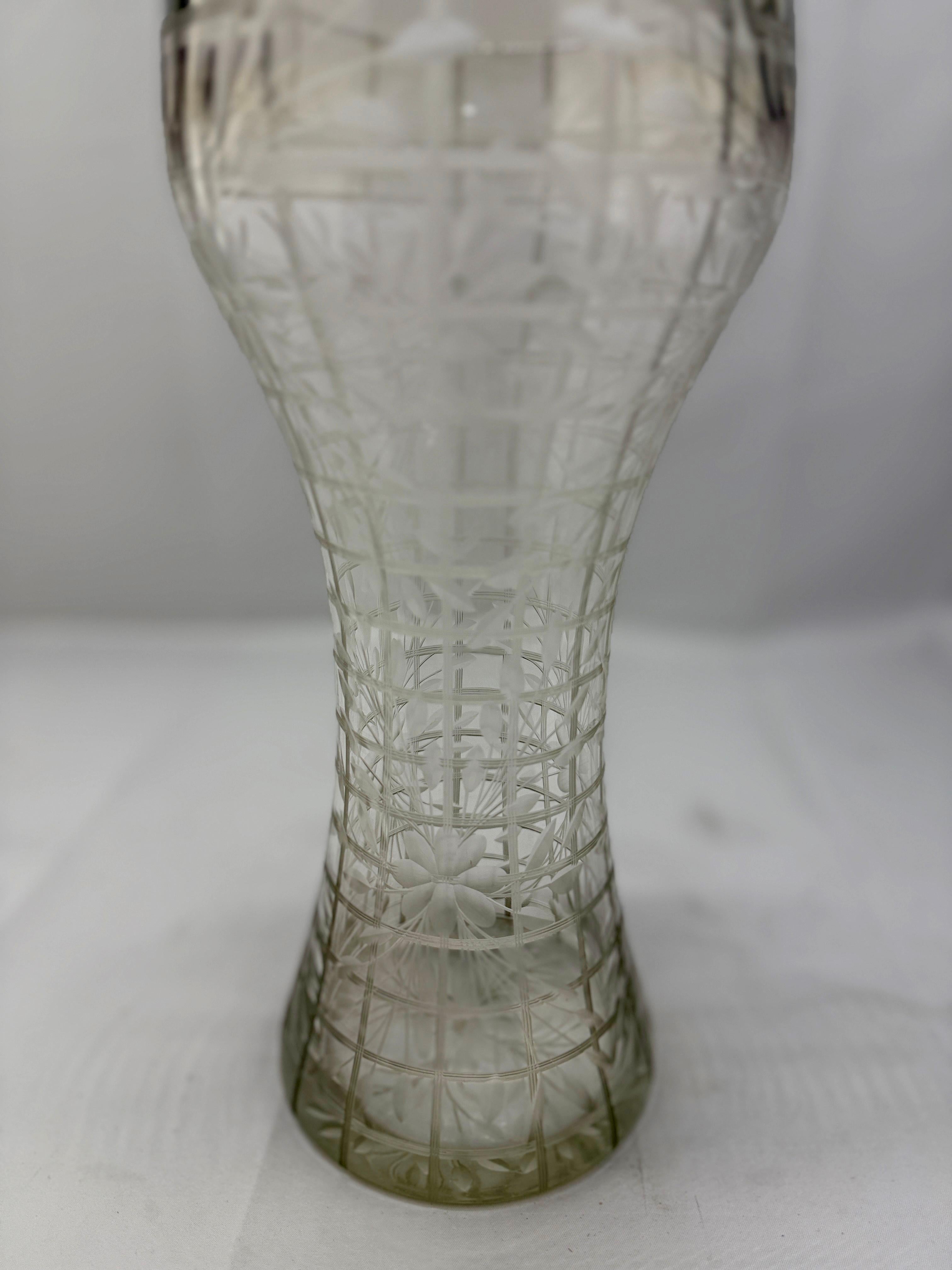 This remarkable antique American vase is a masterful example of intaglio cut glass craftsmanship from the late 19th to early 20th century. The piece features an unusual design that combines geometric paneling with intricately etched floral motifs,
