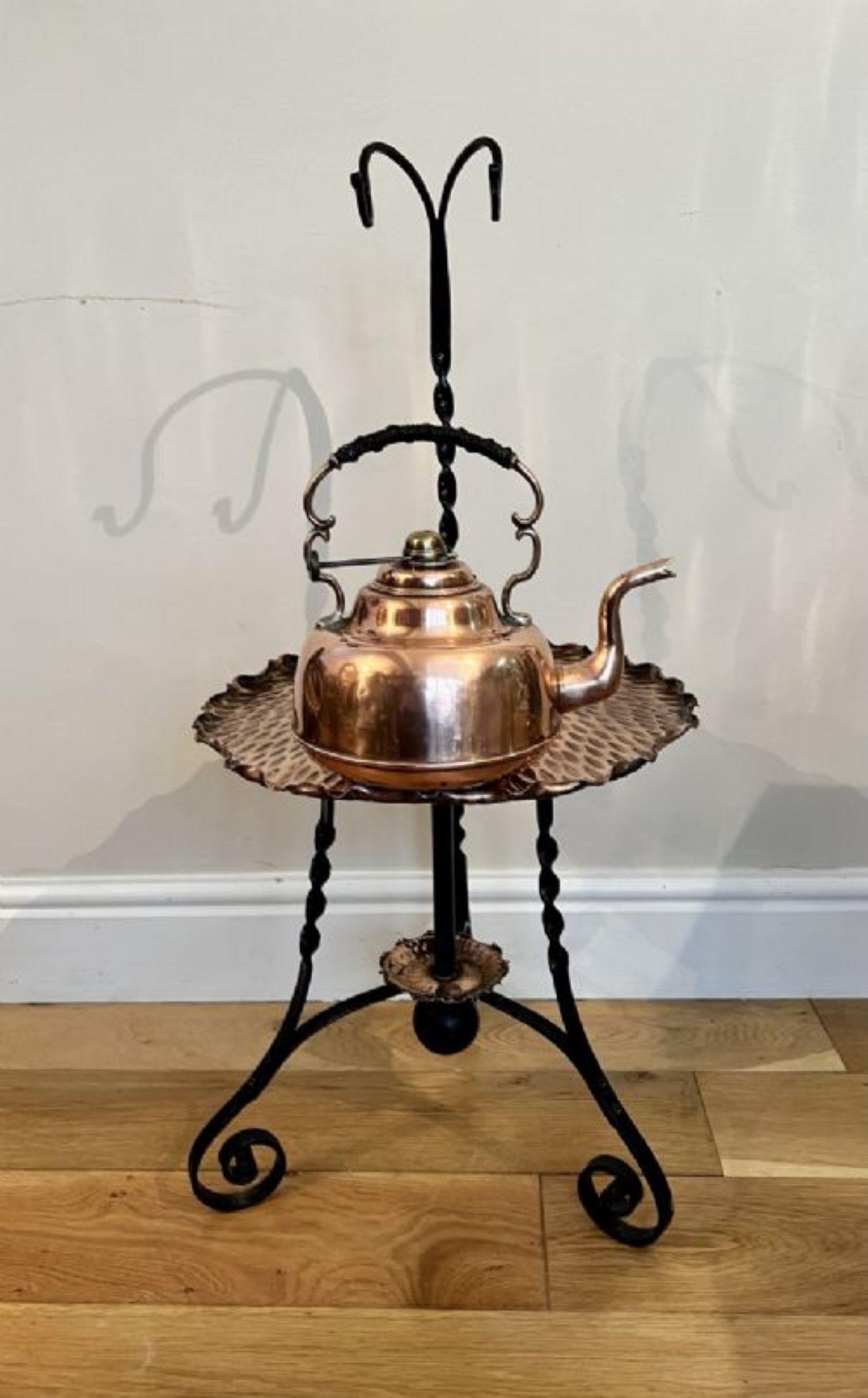 Unusual antique art and crafts quality copper hanging kettle having a quality hanging copper kettle above a shaped copper tray, supported by an iron stand with shaped feet.