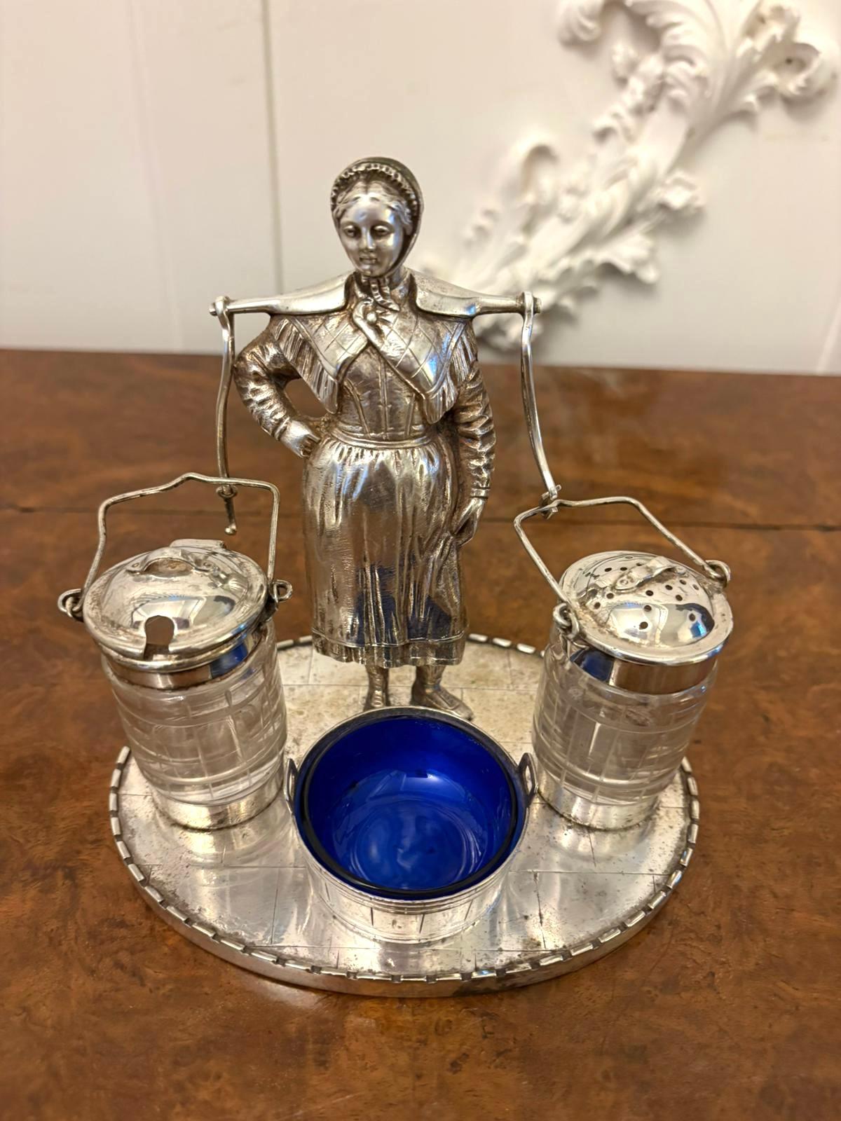 Inusual vasija de plata de calidad eduardiana antigua que consta de un salero, un pimentero y un recipiente de mostaza con la figura de una dama que lleva dos cubos sobre una base ovalada plateada de calidad con un recipiente redondo,  forro azul