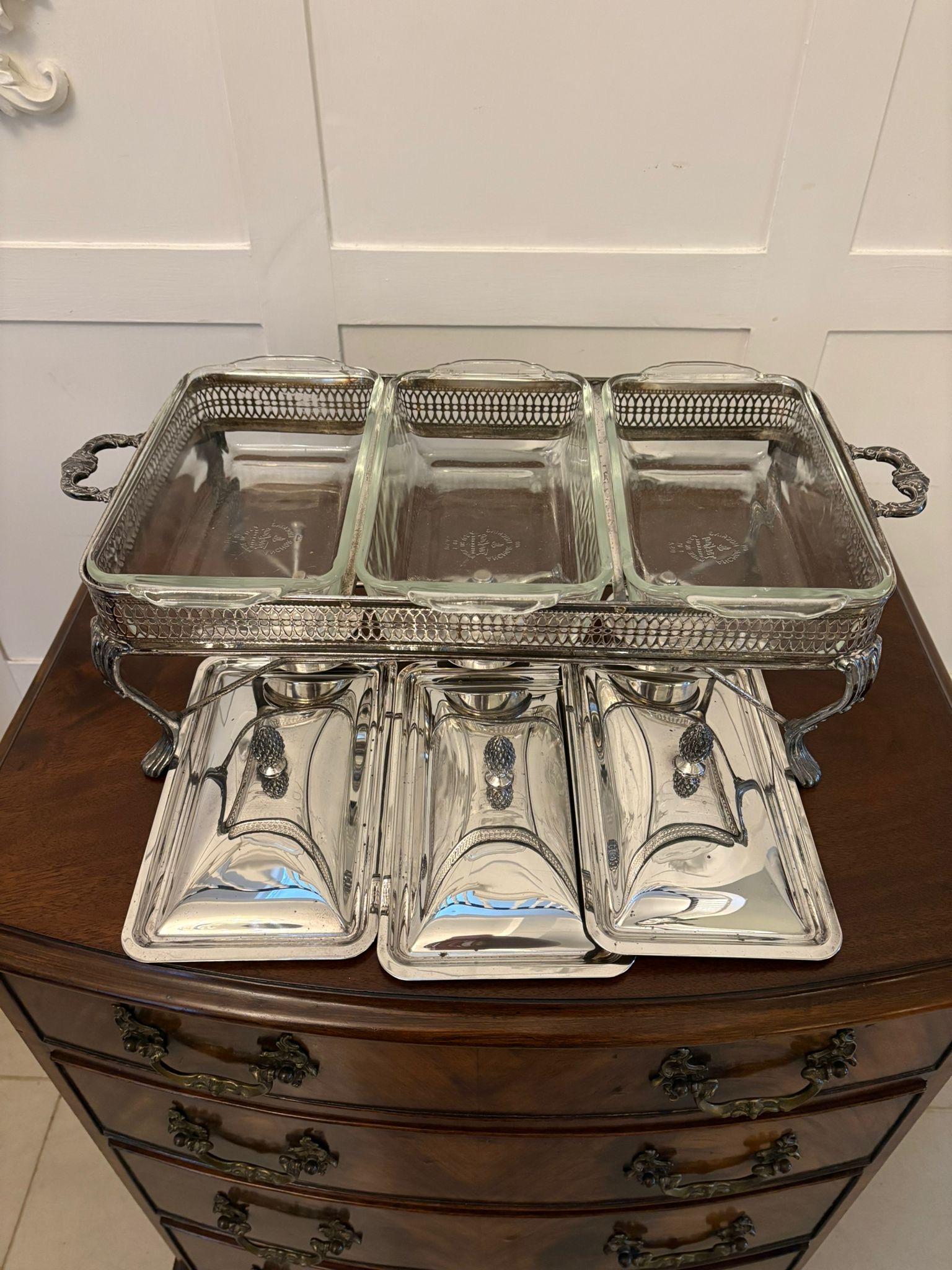 Insólita vajilla antigua eduardiana de tres platos plateados para servir sobre un soporte calentador, con tres tapas de calidad bañadas en plata que se levantan sobre cuencos de cristal apoyados en una galería ornamentada perforada con dos asas,