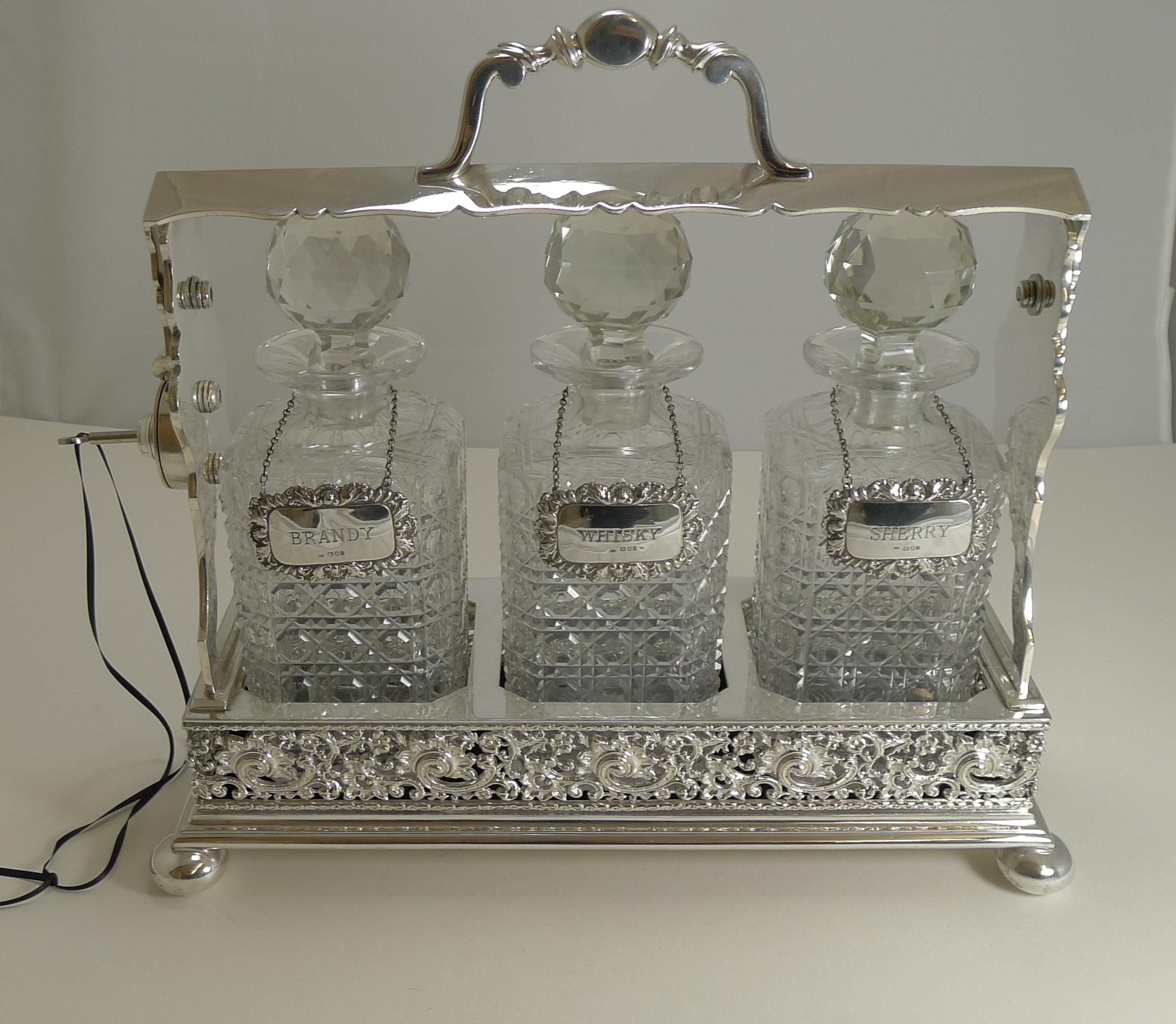 A smart late Victorian three bottle Tantalus with three cut crystal decanters in the ever-popular hobnail design.

The frame is most unusual with a cast pierced or reticulated base. Once unlocked, the barrel is slid down to release the bar