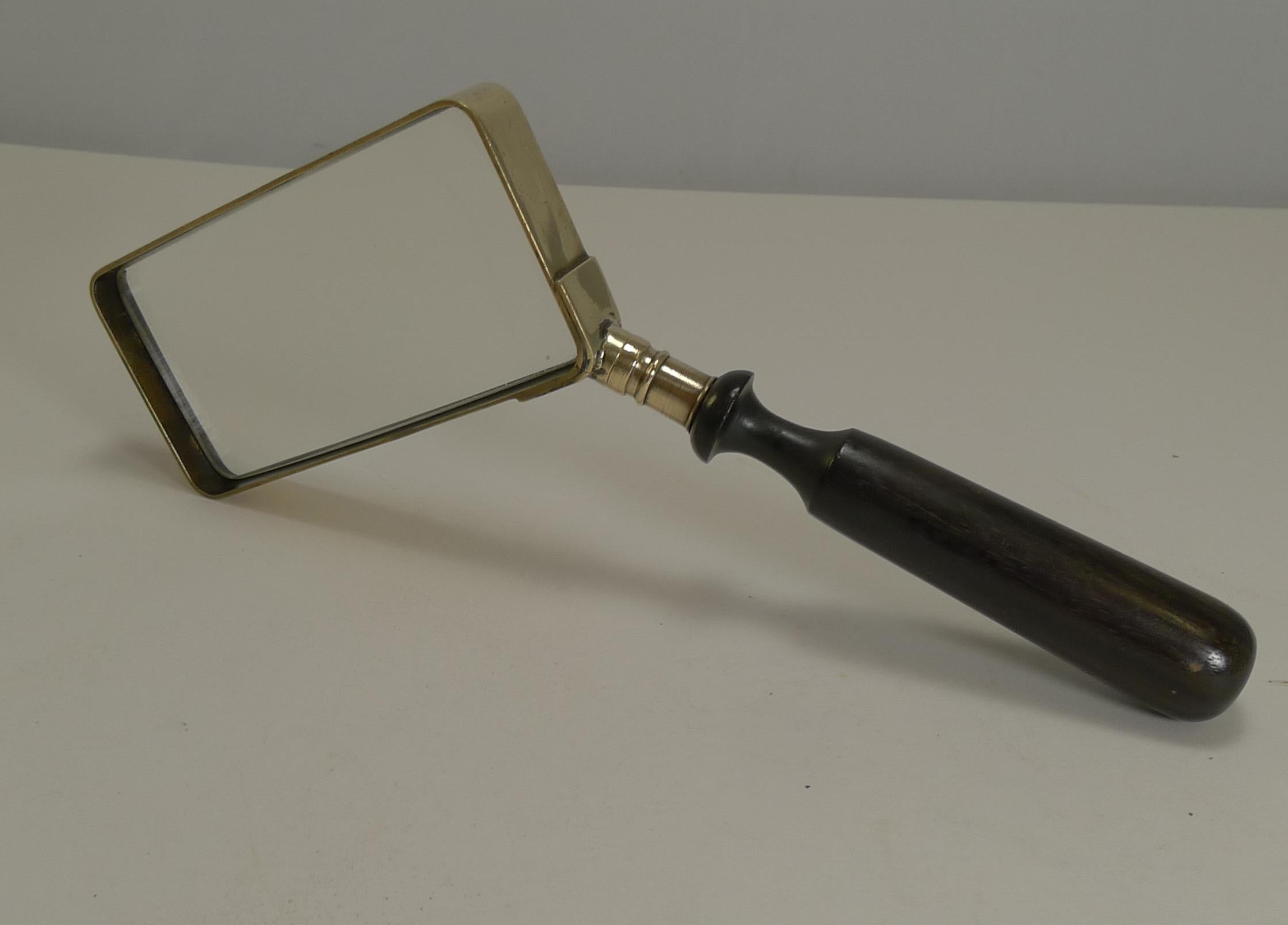 A handsome Edwardian brass framed rectangular magnifying glass polished to gleam. The handle is made from turned ebony wood and unusually and conveniently to the side making it a very usable piece to read with.

Dating to circa 1900, the glass is